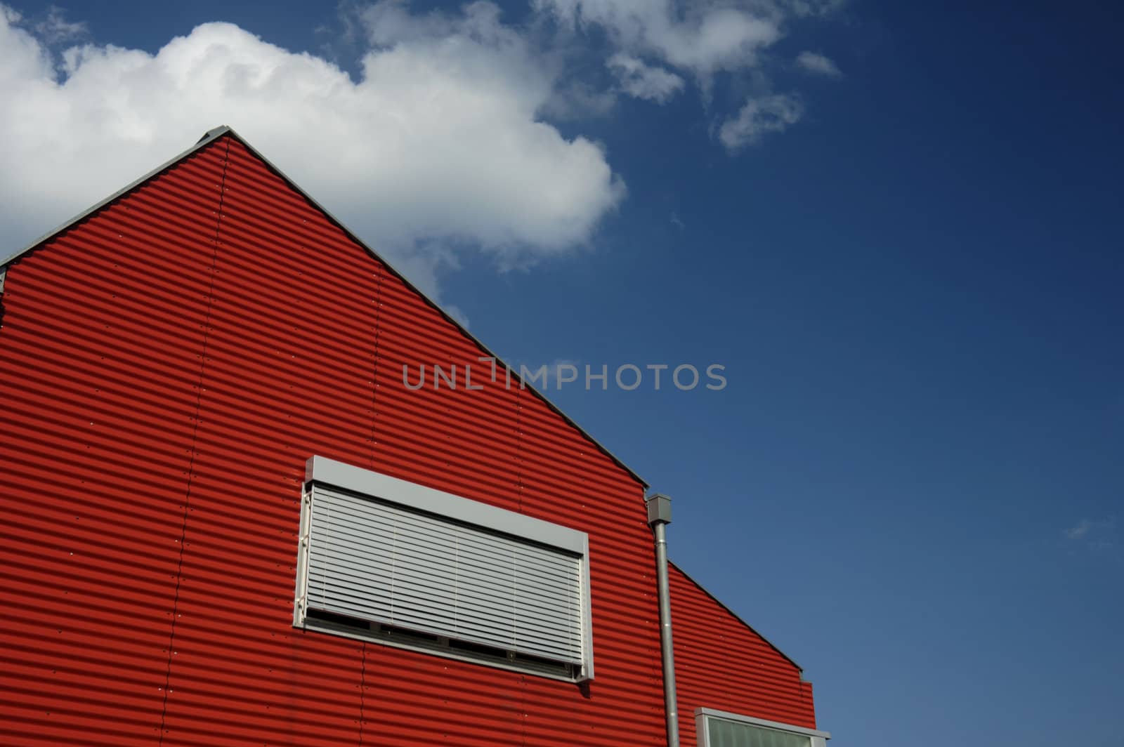 The red end of a building, against a blue summer sky. Space for text in the sky.