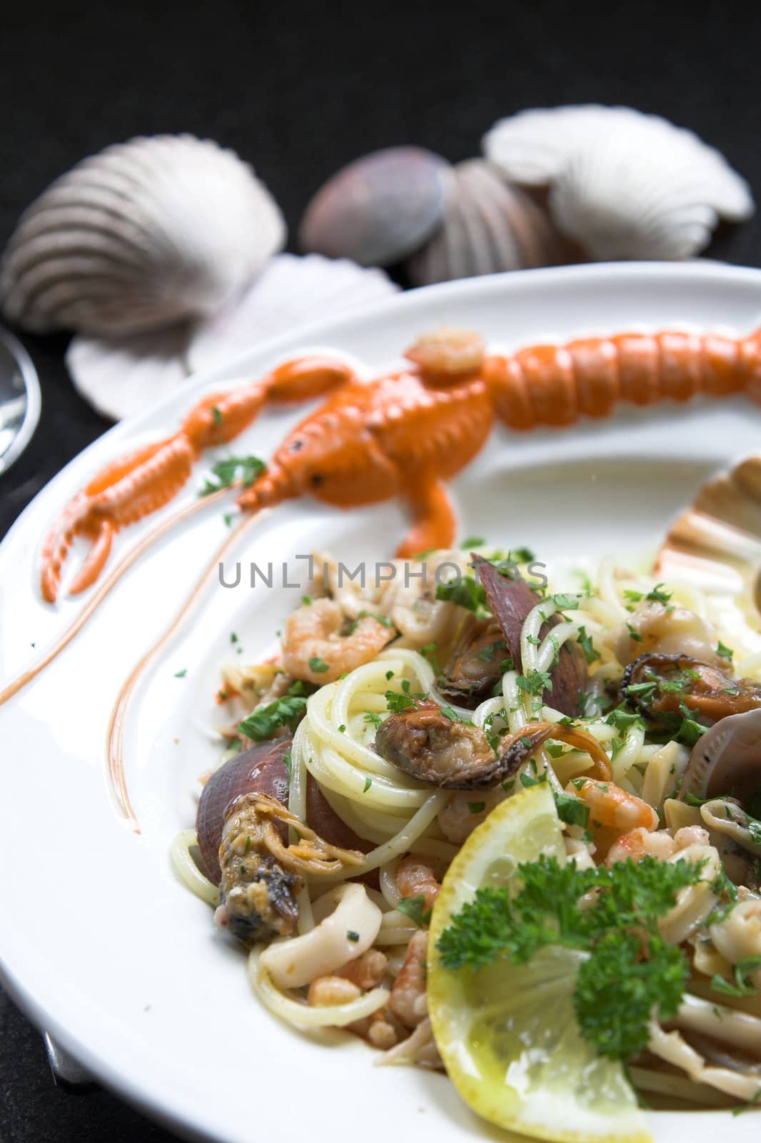 Spaghetti dish with seafruit served on a seafruit plate with some shells in the background