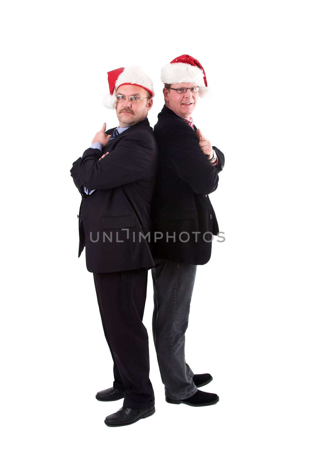 Two man standing on white background with their backs against each other wearing christmas hats