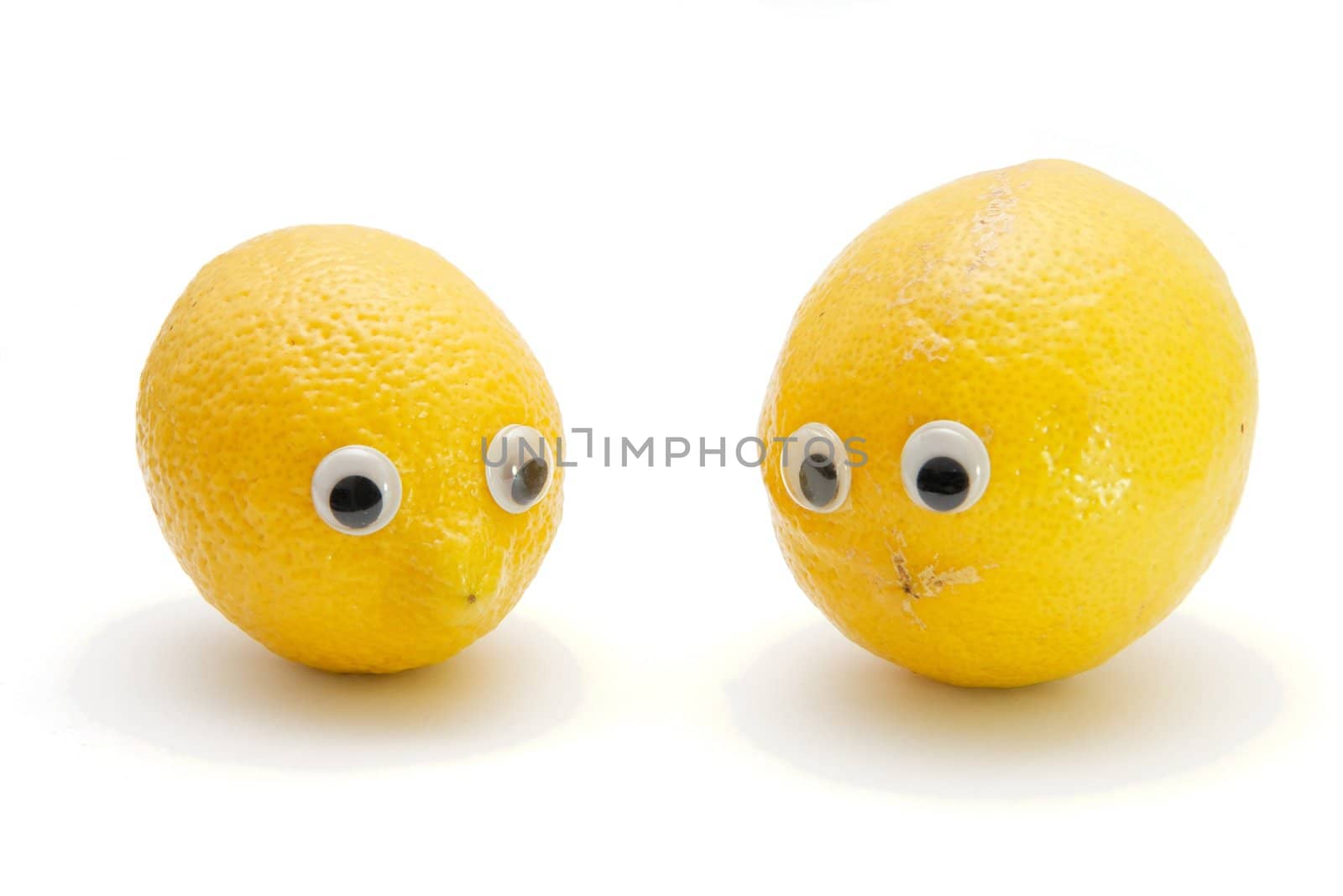 Two funny lemon fruits with eyes on white background