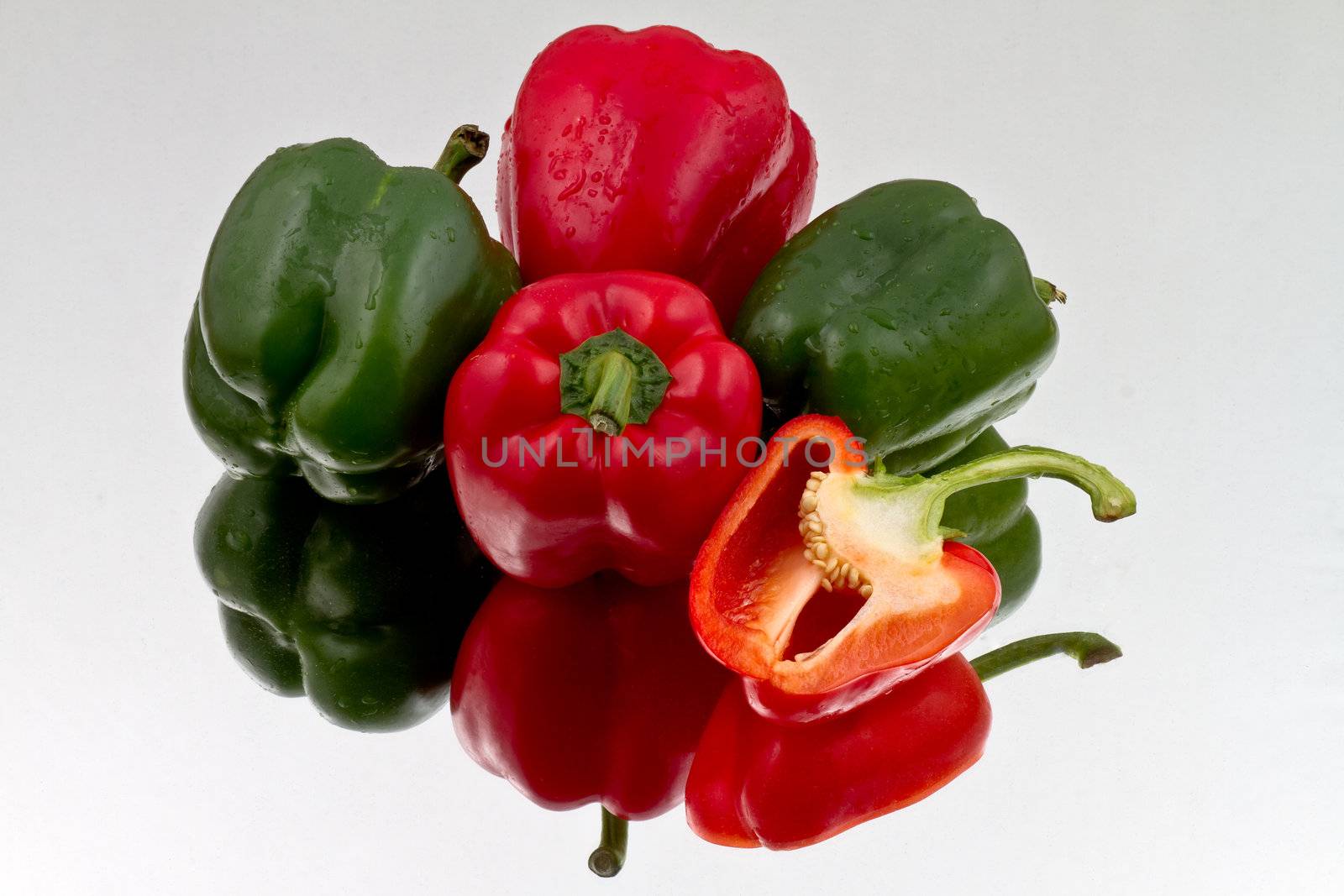 Red and green bell peppers on reflective bacground by lavsen