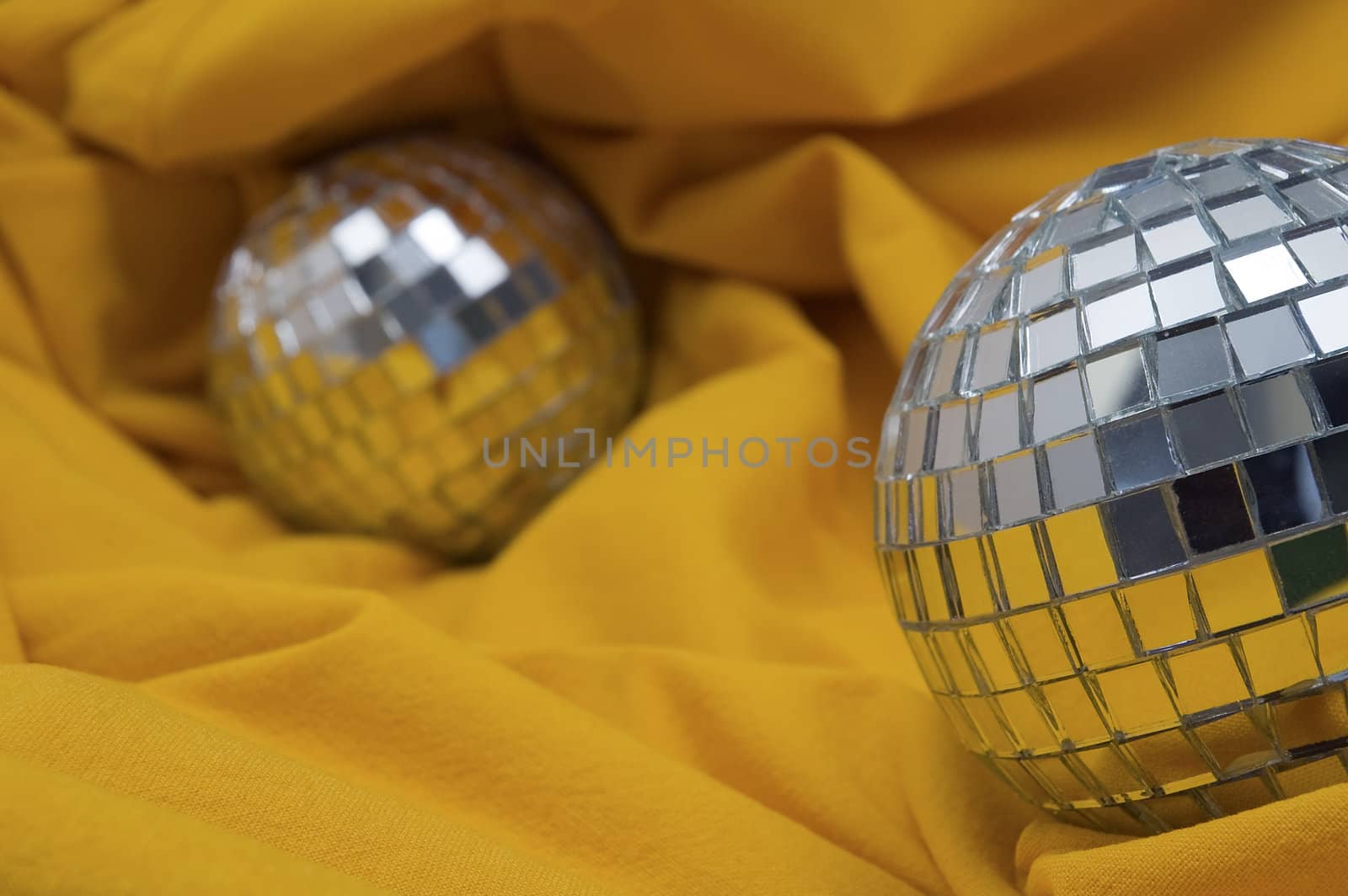 two disco balls on yellow background, shallow depth of view