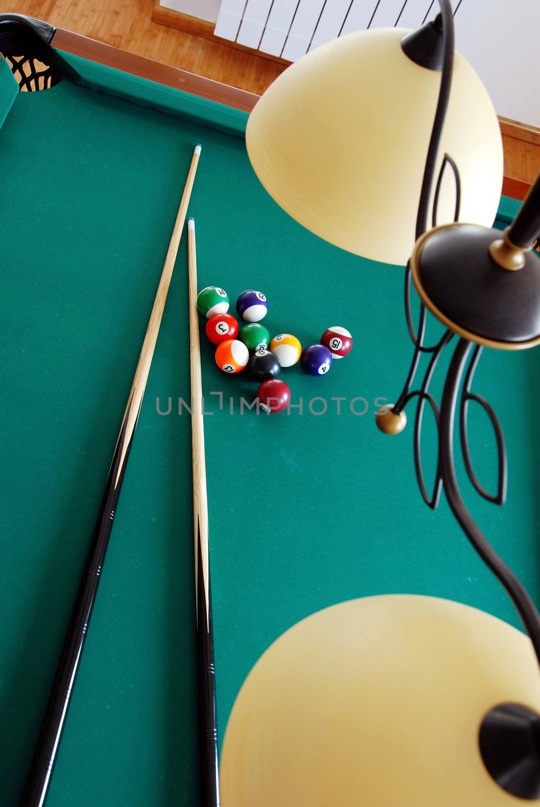 lamp over billiards green table with balls and two black cues