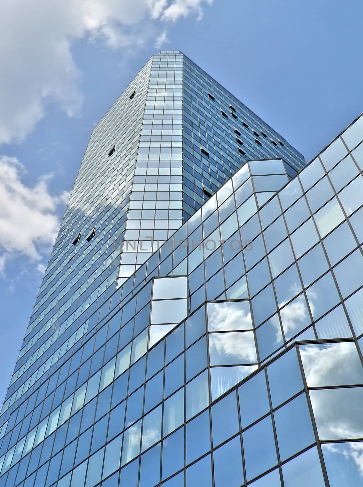 Glass building in Warsaw under blue sky with clouds