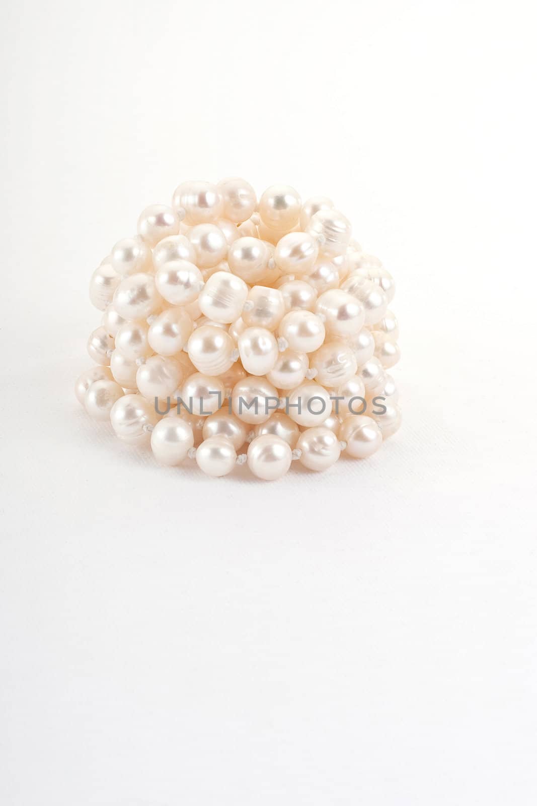 Reeled up pearl necklace on white background