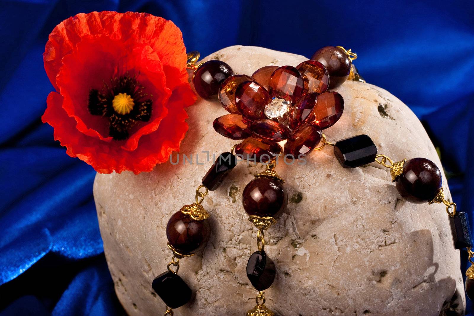 Necklace, flower and stone on a blue textile