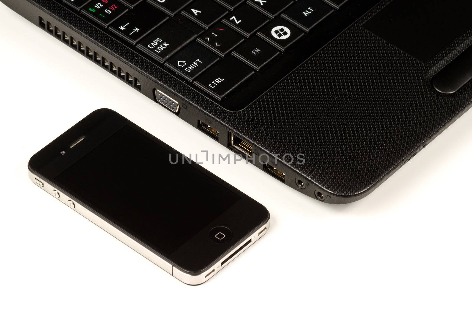 Close-up of a black smartphone and a black laptop on white background