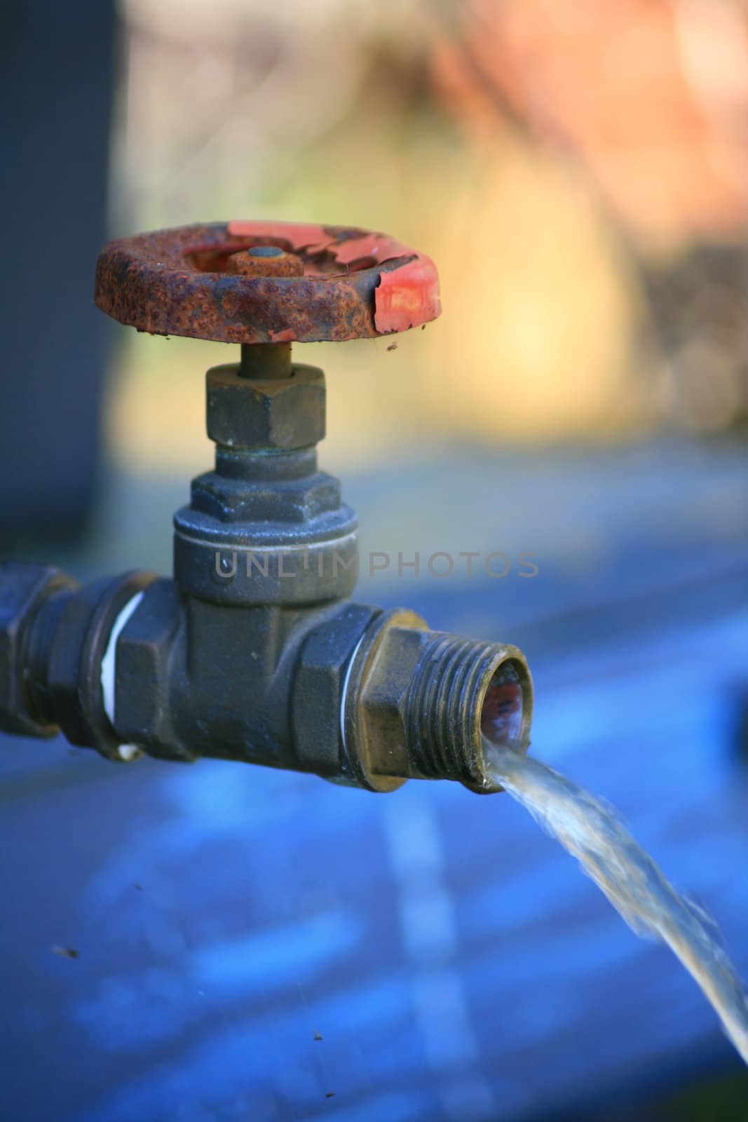 A rusty outside tap running with water.