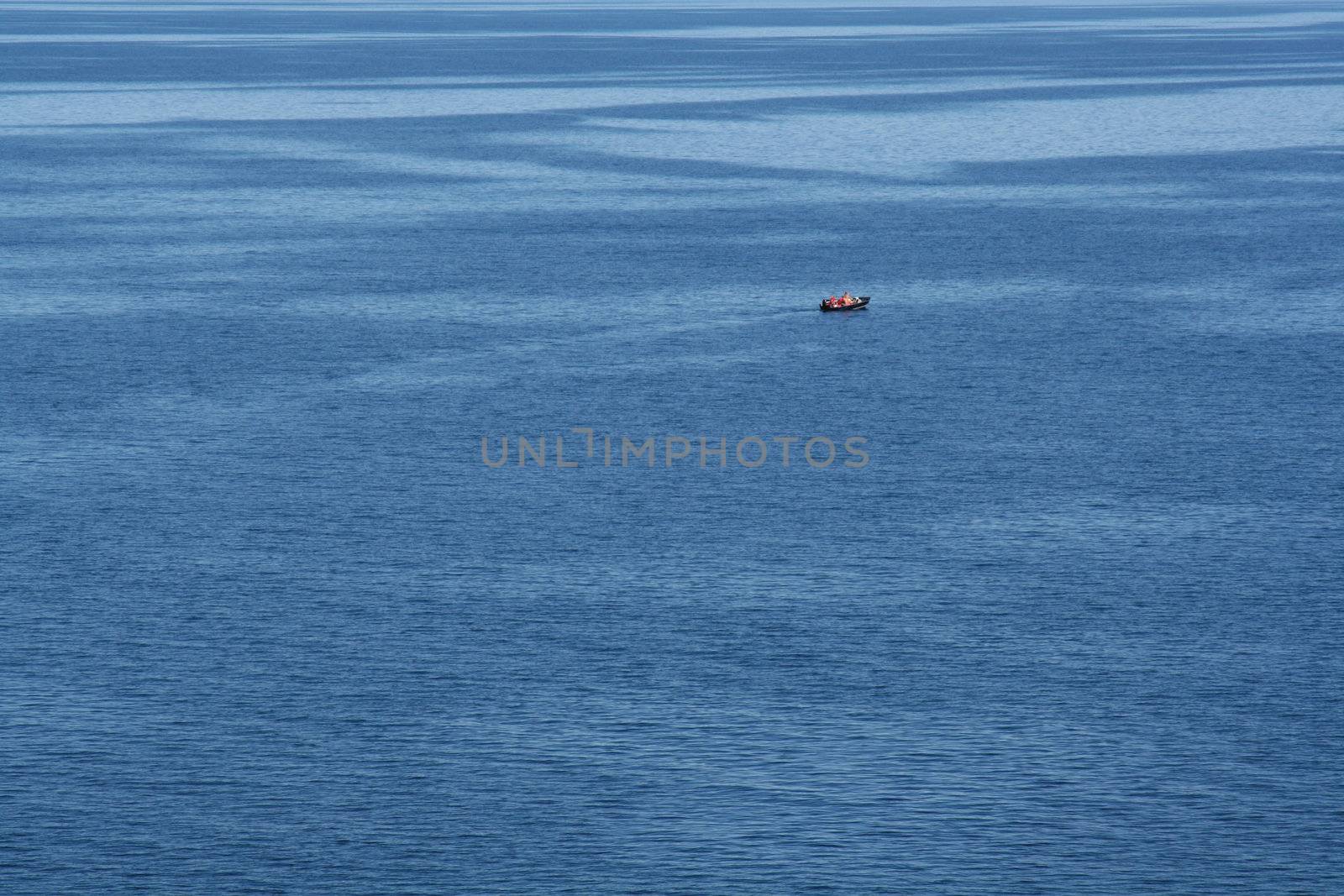 A small boat with a couple occupants in the middle of the open ocean.