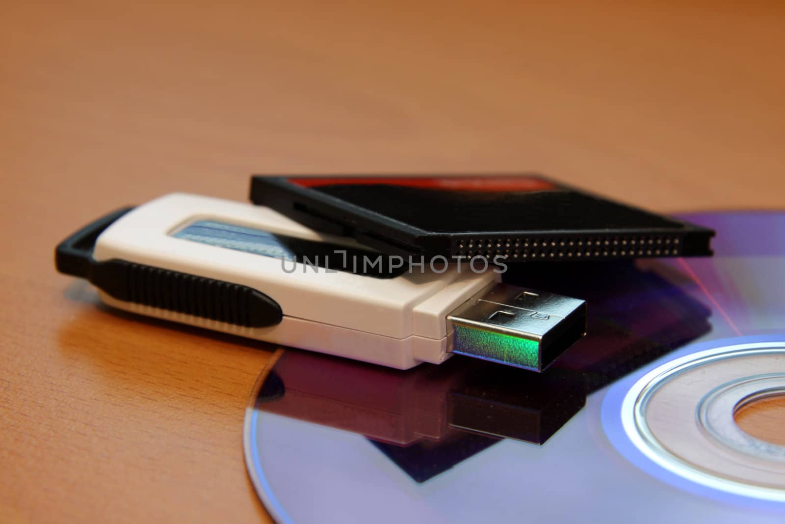 Three different pieces of media storage. (USB stick, compact flash and a DVD)
