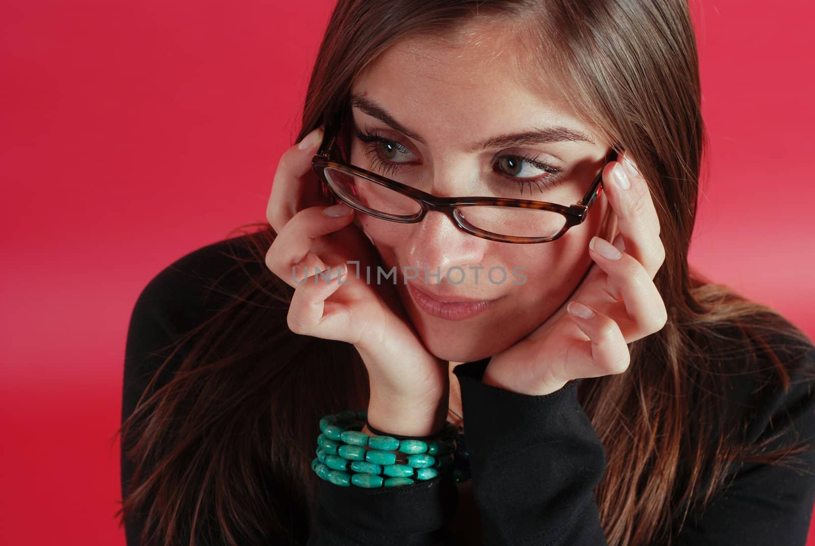 beautiful girl showing off her glasses on a red background