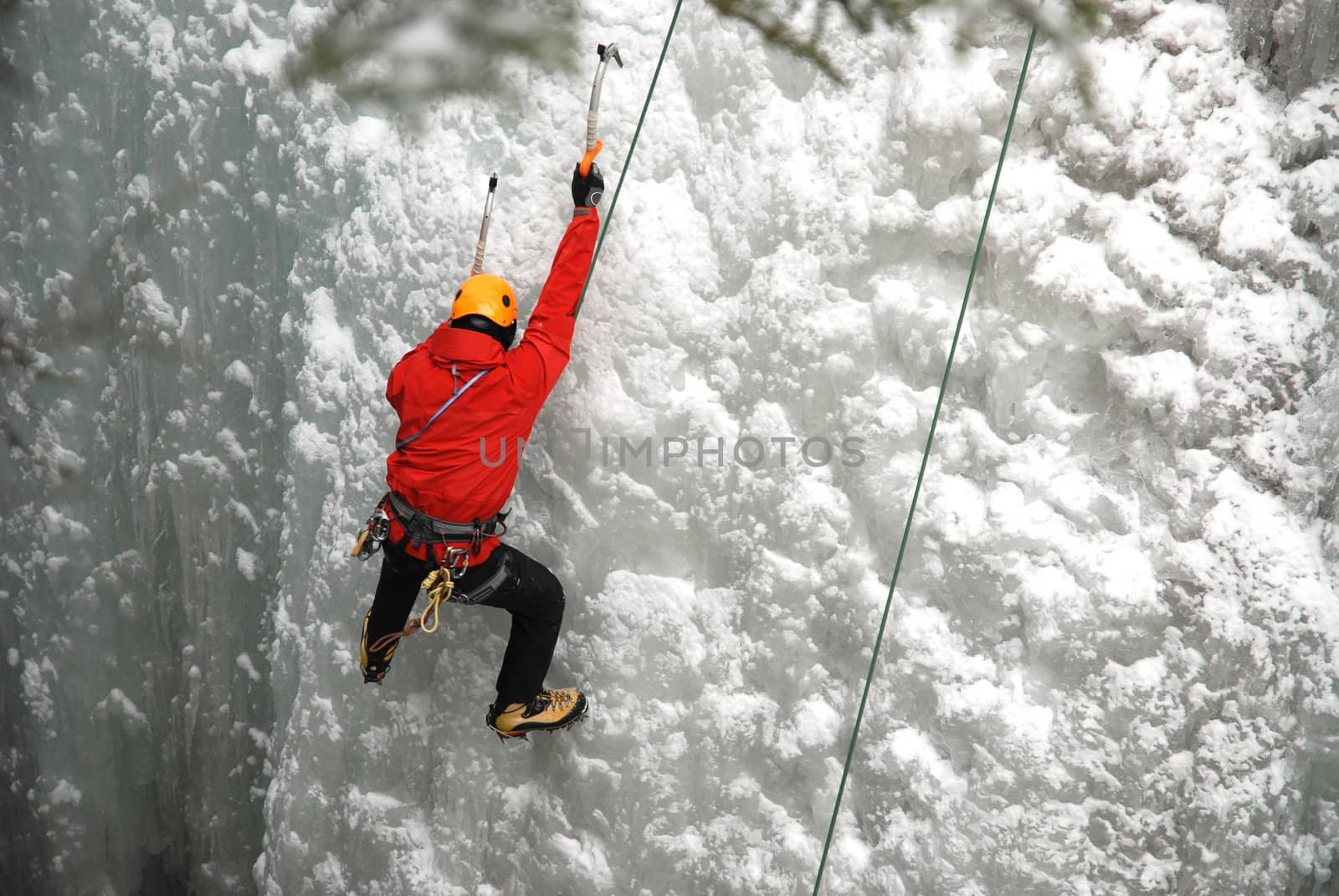 An Ice Climber going up a frozen waterfall.