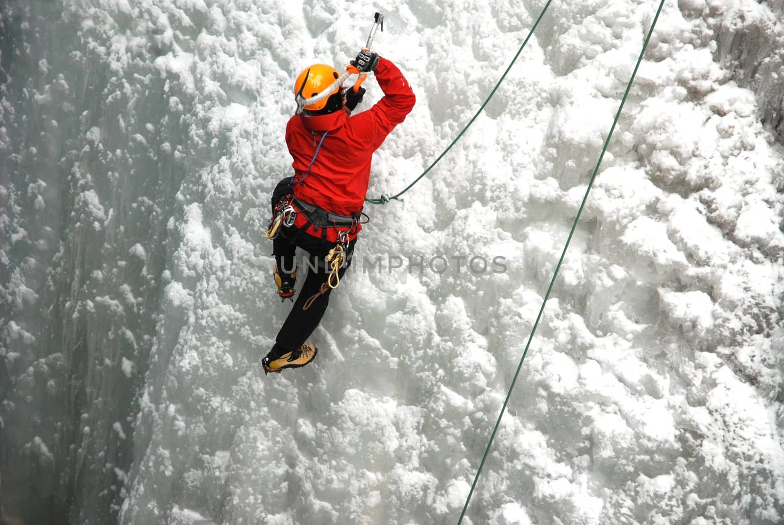 An Ice Climber going up a frozen waterfall.