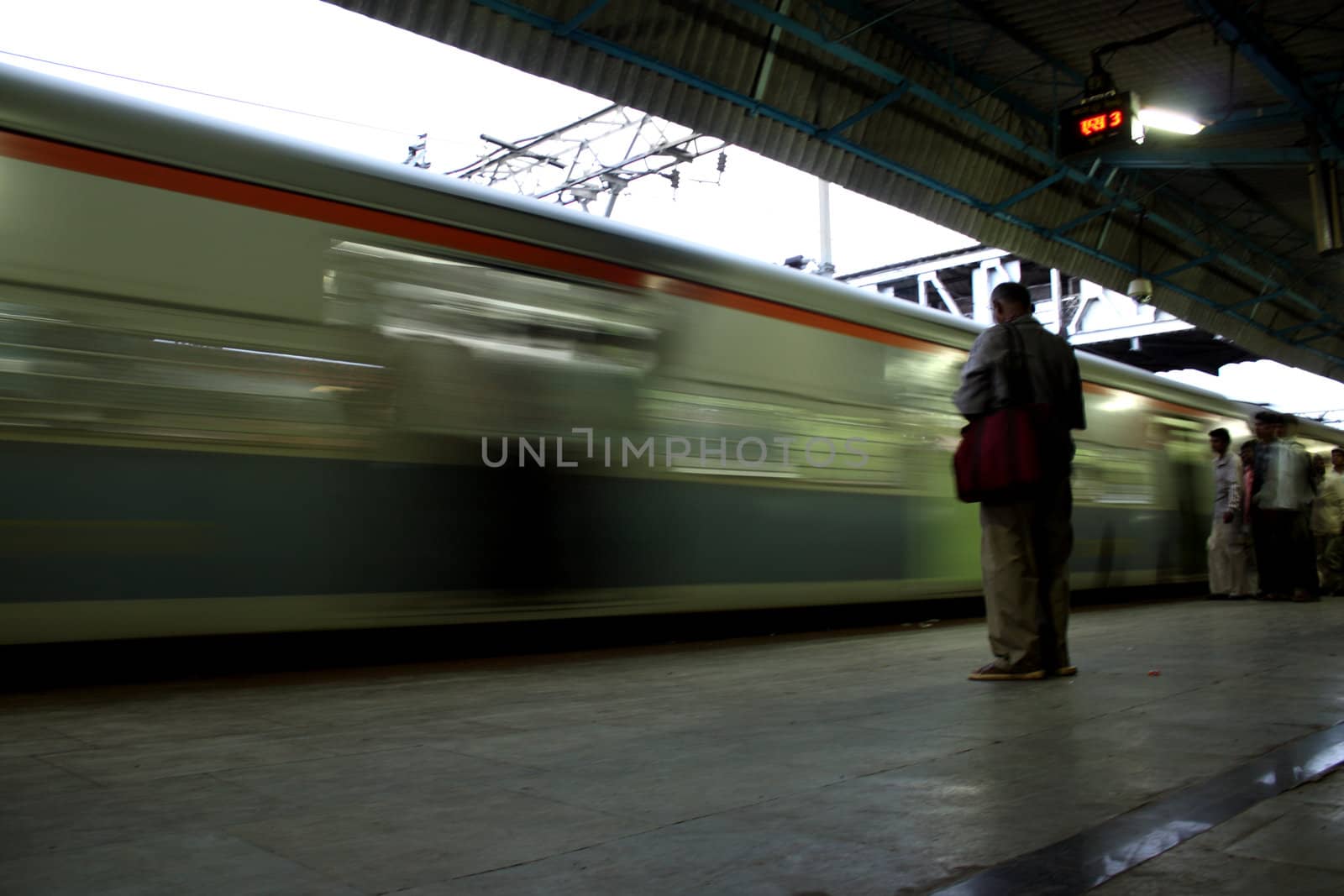 A commuter waiting for his train to arrive at an Indian railway station platform.