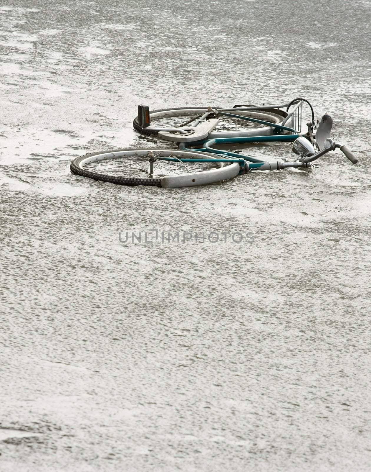 Abandoned, broken bicycle on a frozen lake