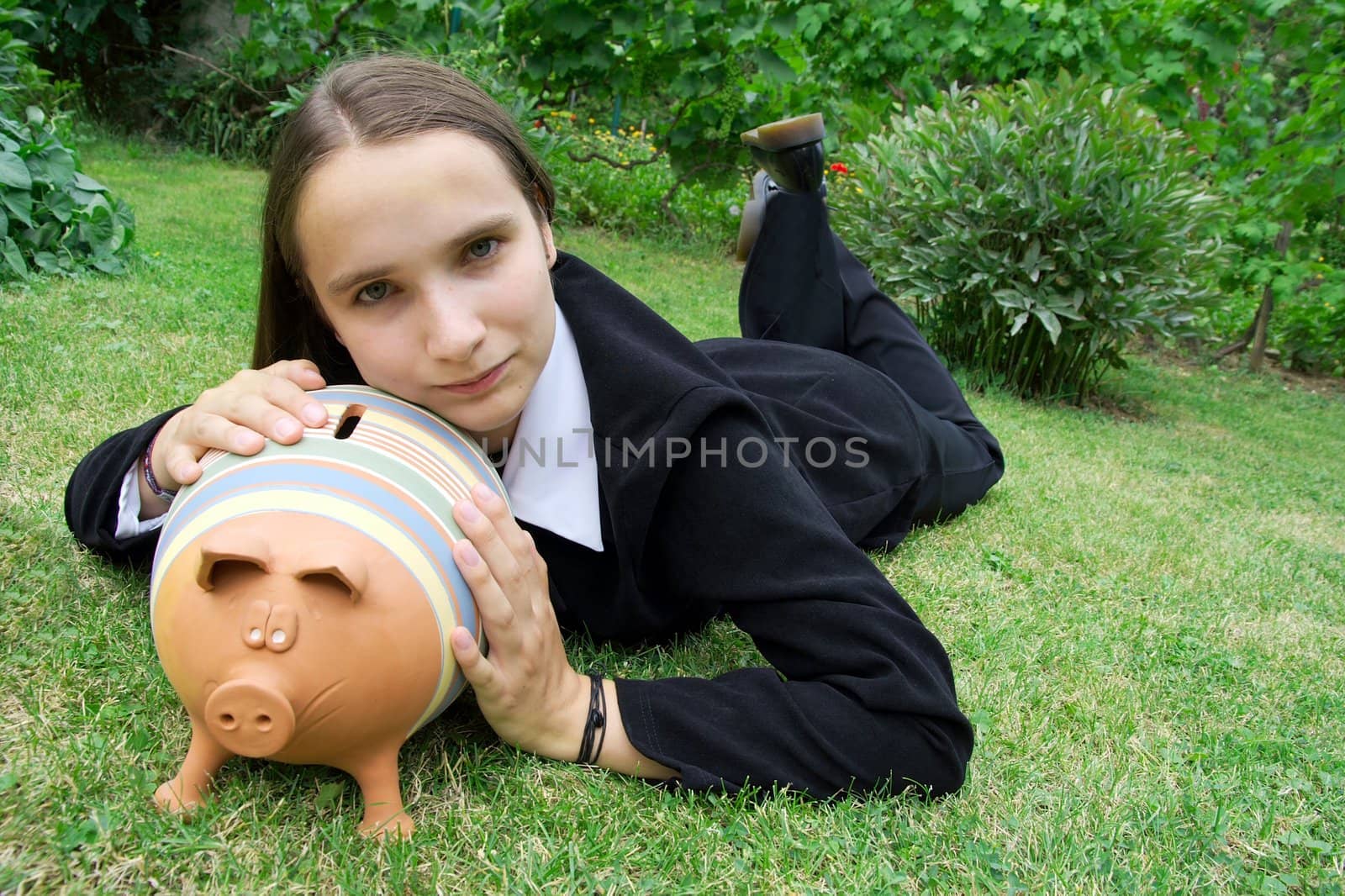 Girl in suit in the park with a piggy bank