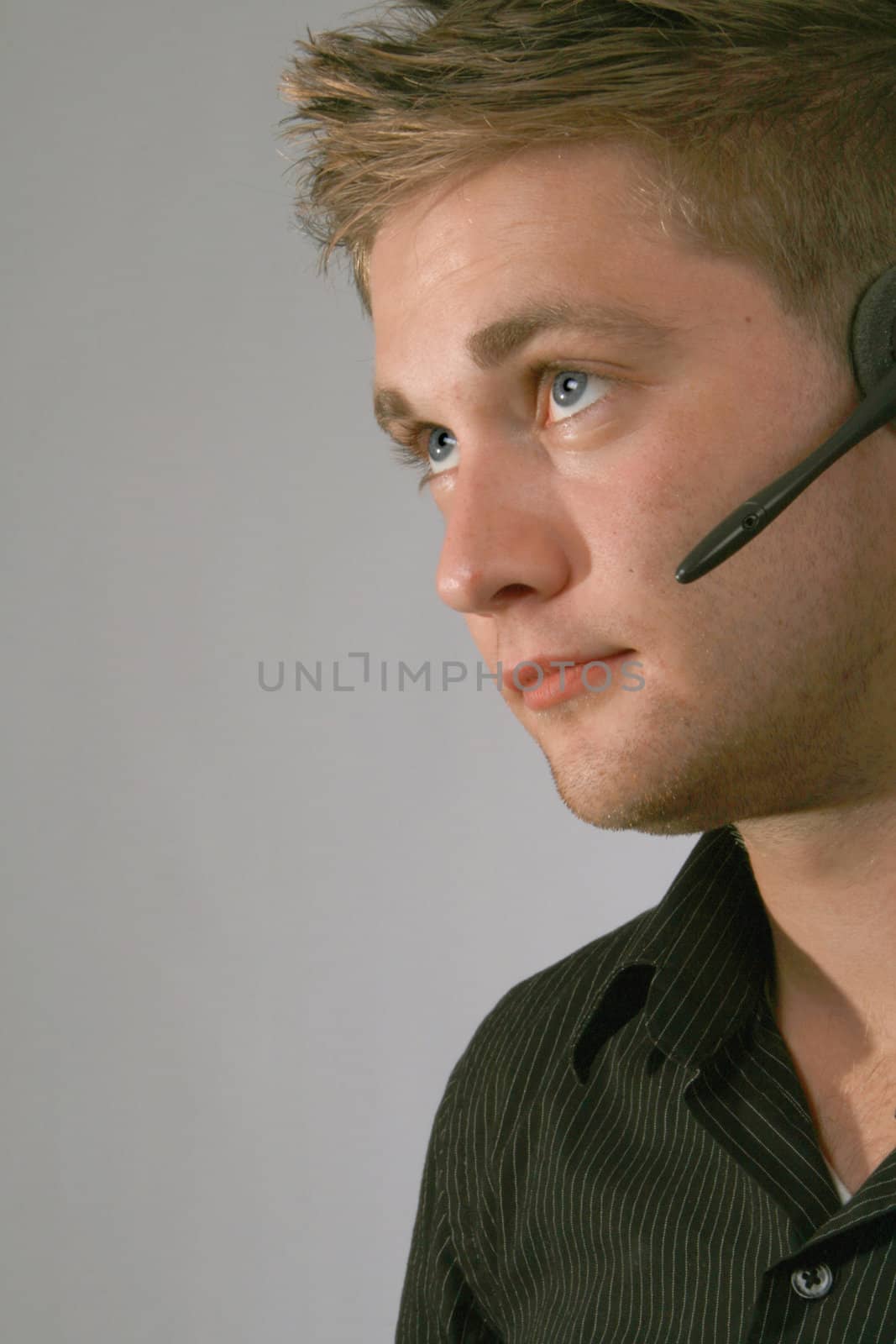 Young businessman wearing a headset on grey