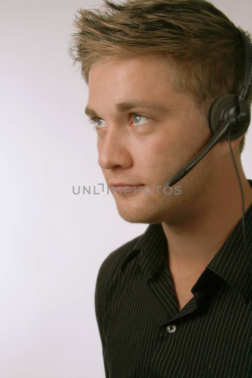 Young businessman wearing a headset on grey