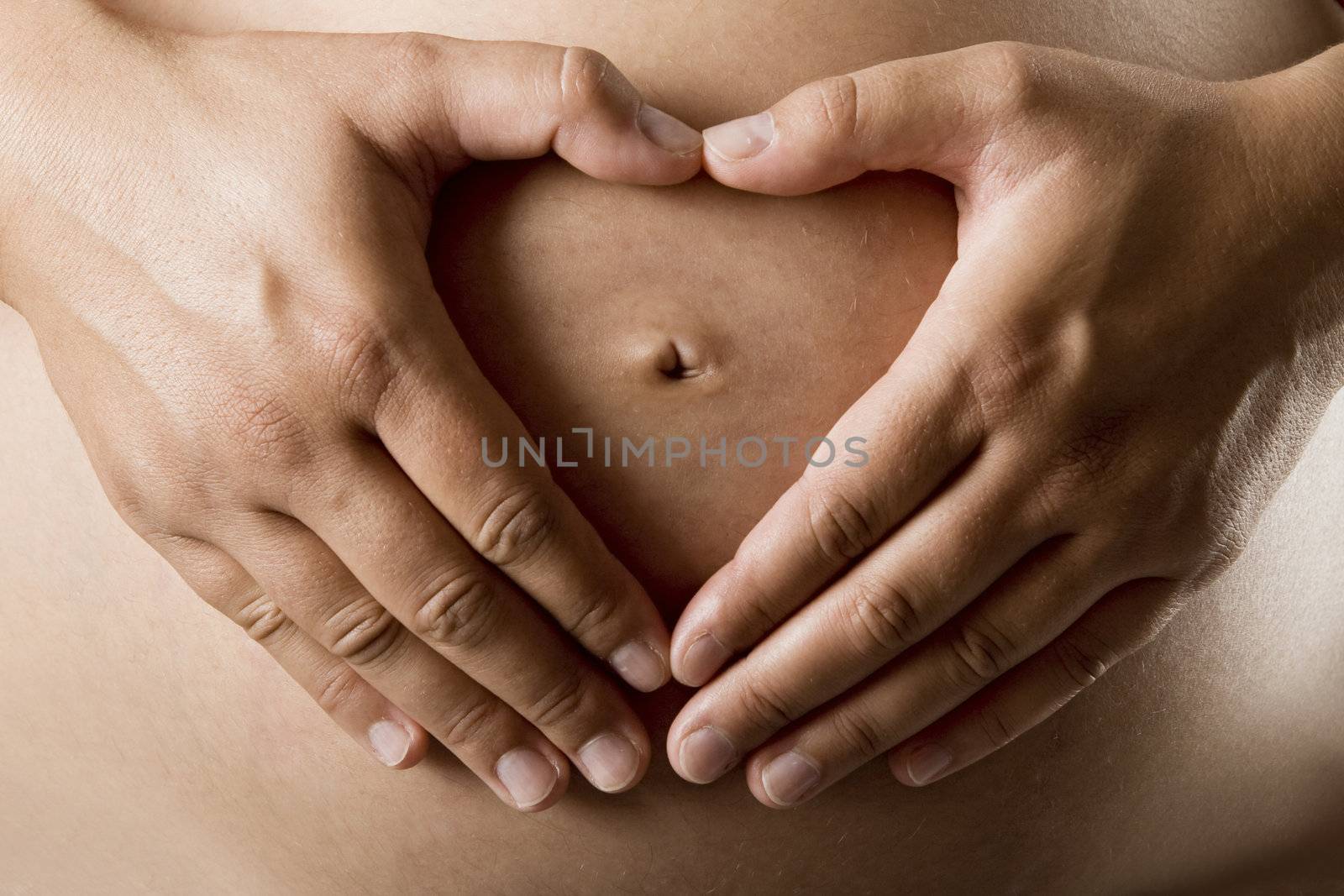 Pregnant women wrap her arms around the belly in the form of the heart. Isolated on white. 