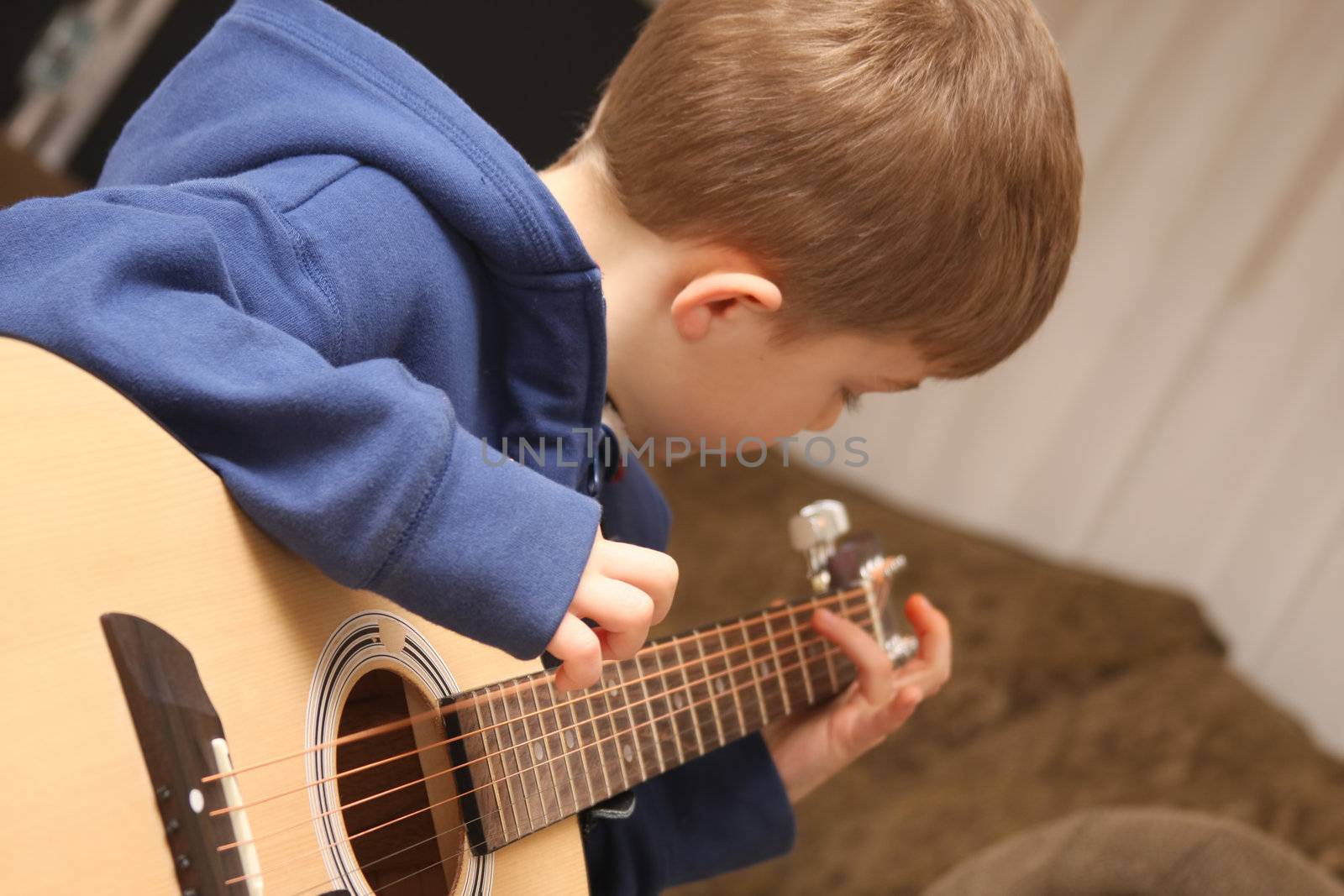 Young Boy strumming the guitar during lessons.