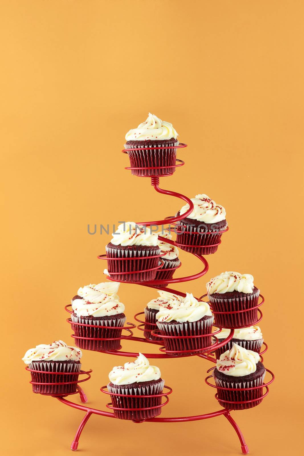 Red velvet cupcakes in a red cupcake holder against a yellowish orange background with copy space included.