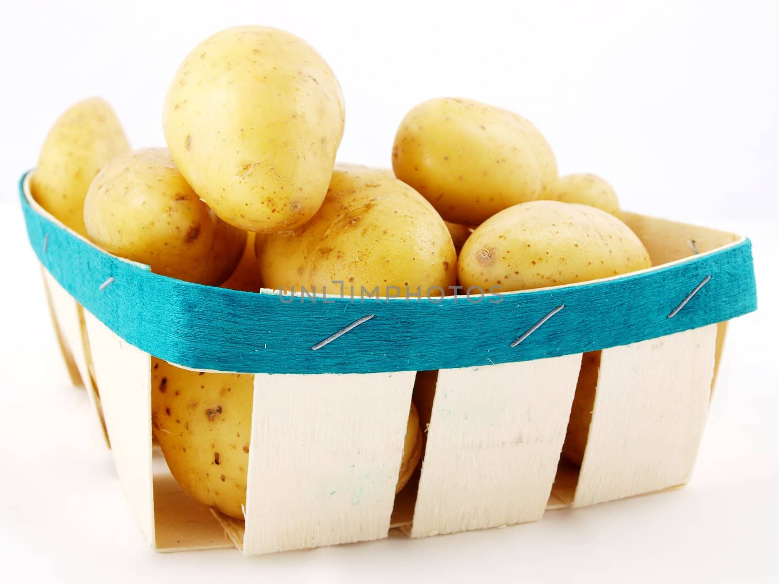 Fresh potatos with shell, in a basket towards white background