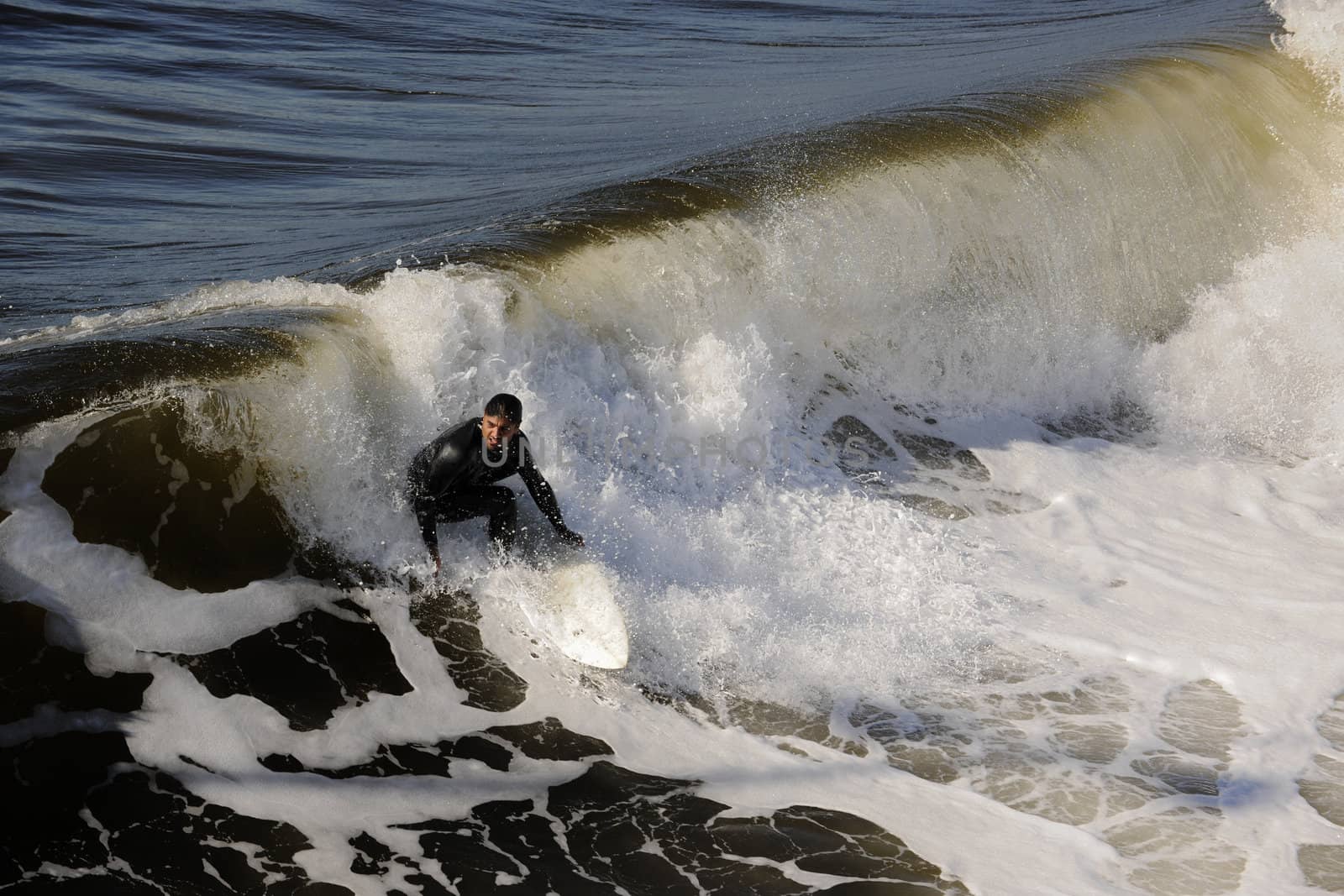 Surfer gets up on a wave. The wave twists with foam and splashes.