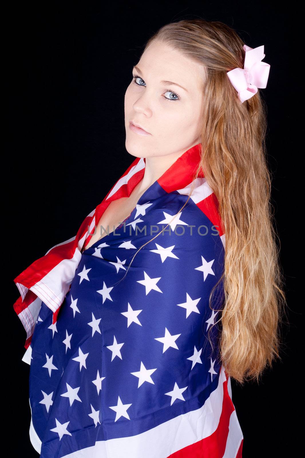 A serious woman with a flag drapped around her.  She does not take her liberty lightly.
