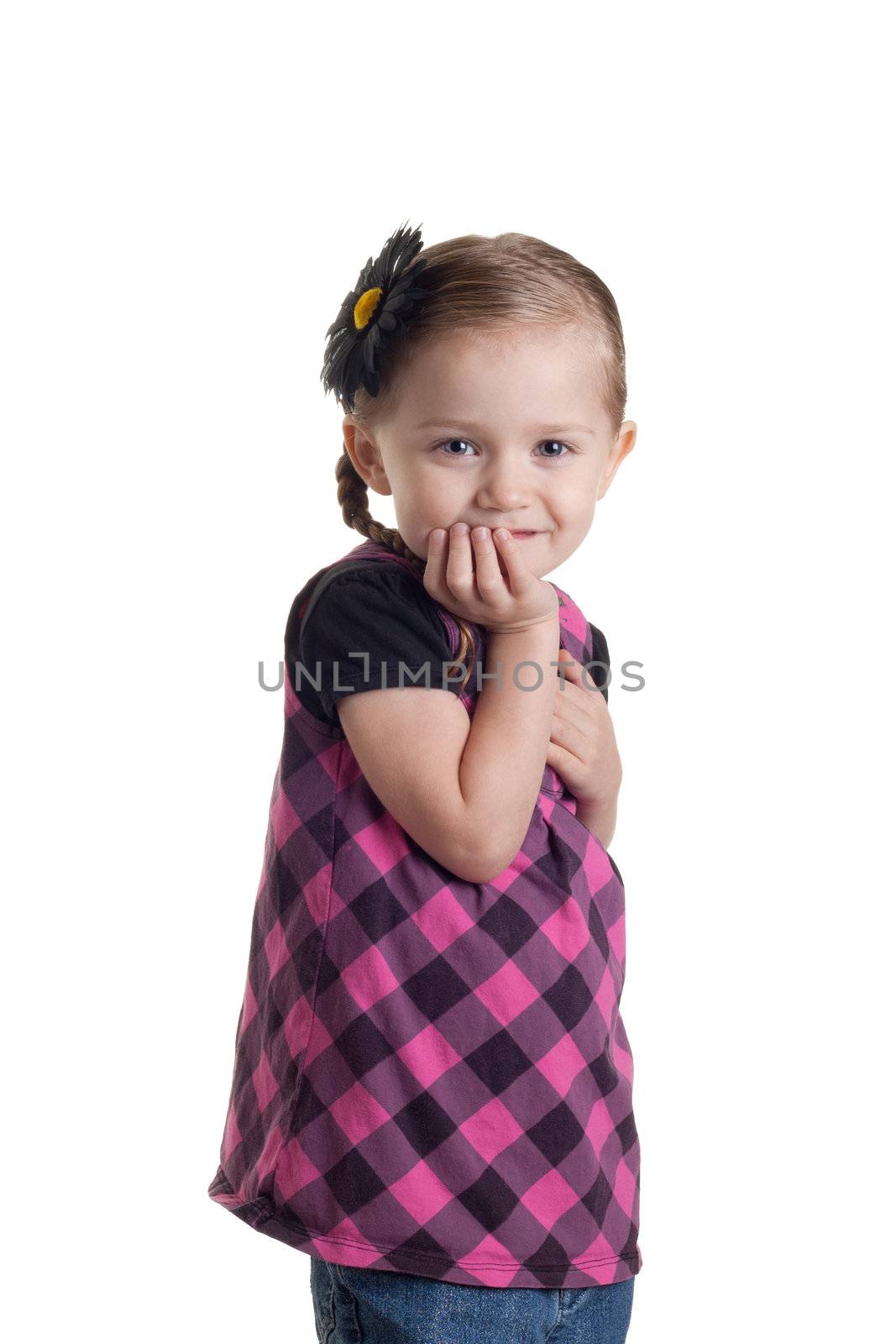 An adorable young toddler girl standing with her hand under her chin.