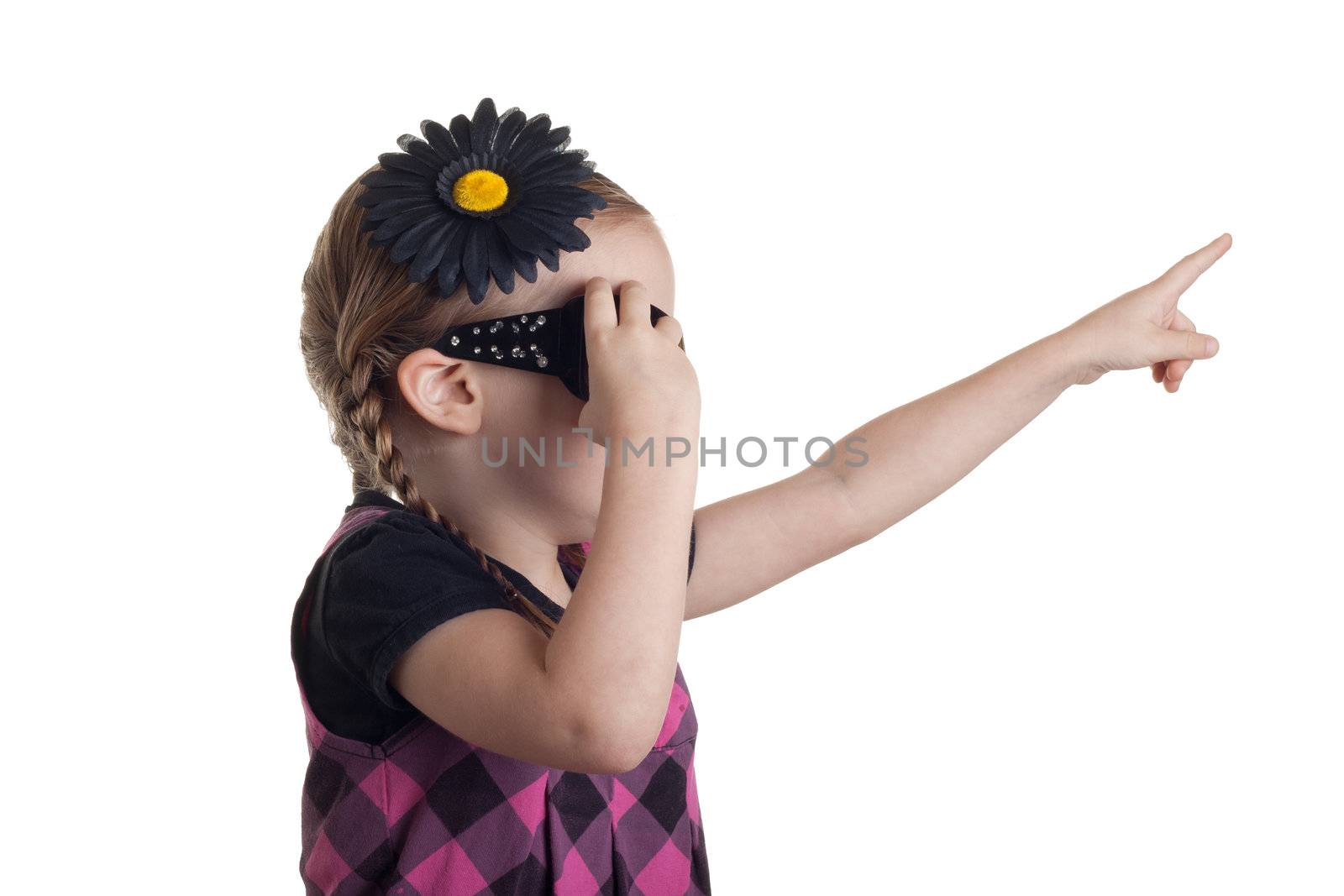 A girl pointing up in the are at something, as she grabs at her sunglasses to remove them.
