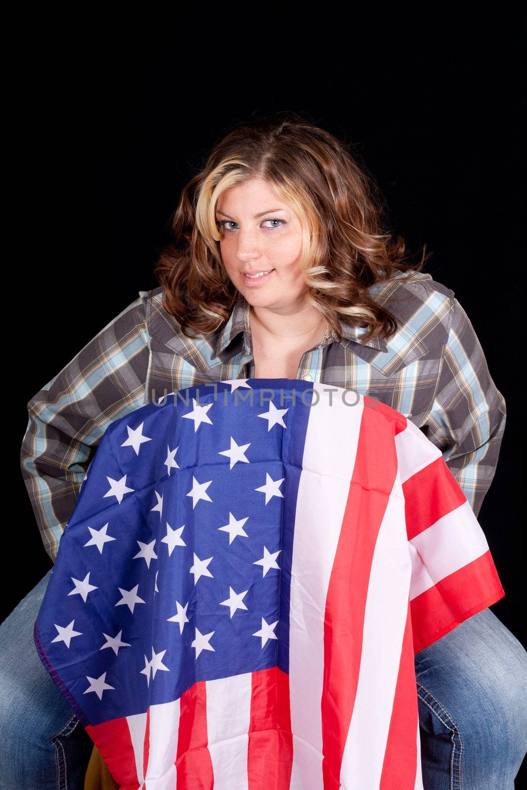 An American Cowgirl sitting on a chair with a flag on it.