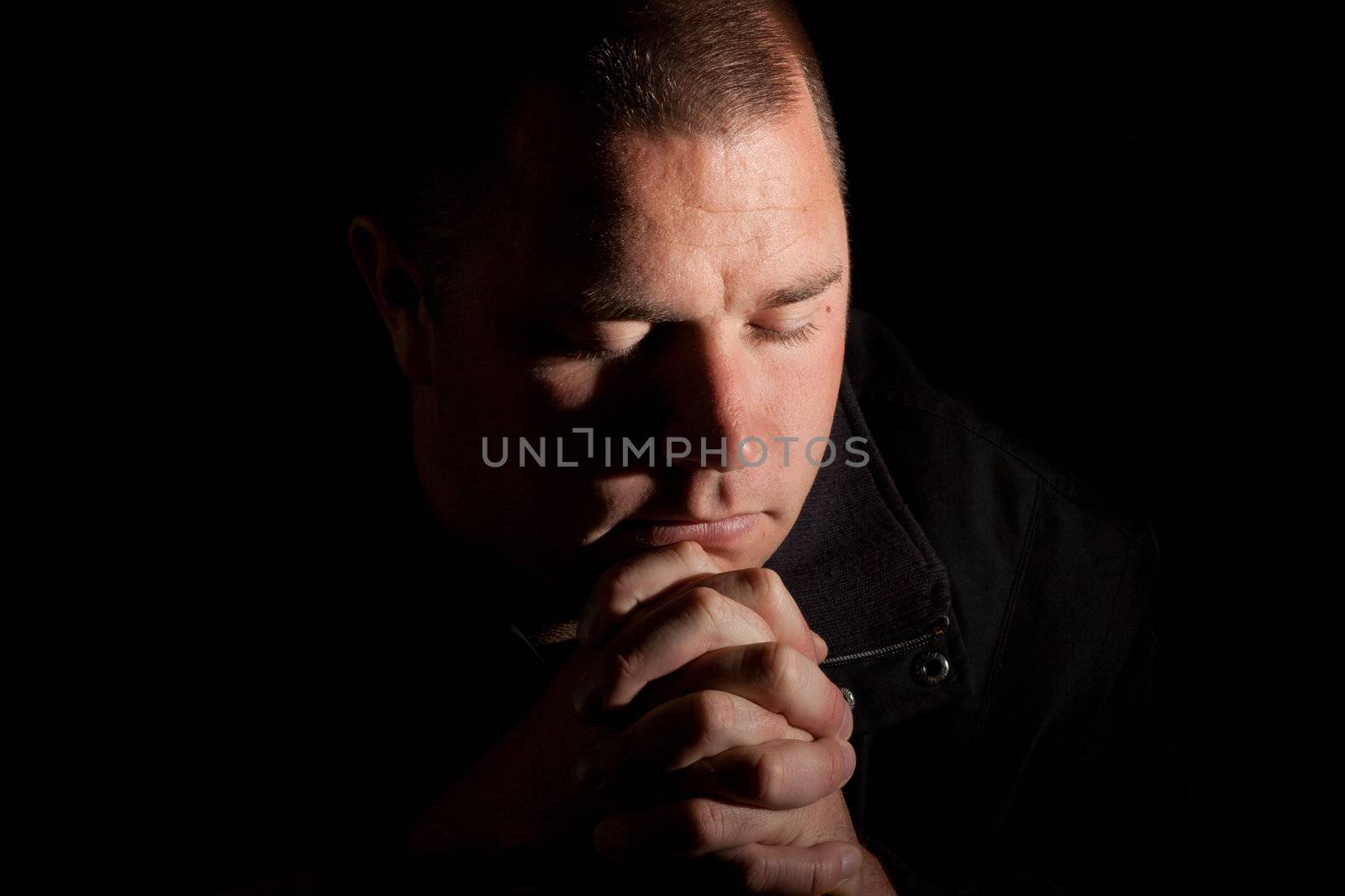 A man praying with holy light coming from above.  He could be worshiping, or just wishing for something.