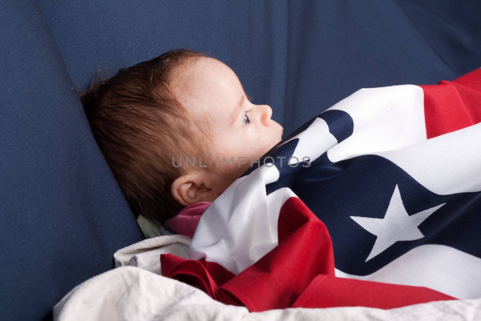 Baby covered with an American Flag pattern.  There is a blue background and room to add text.
