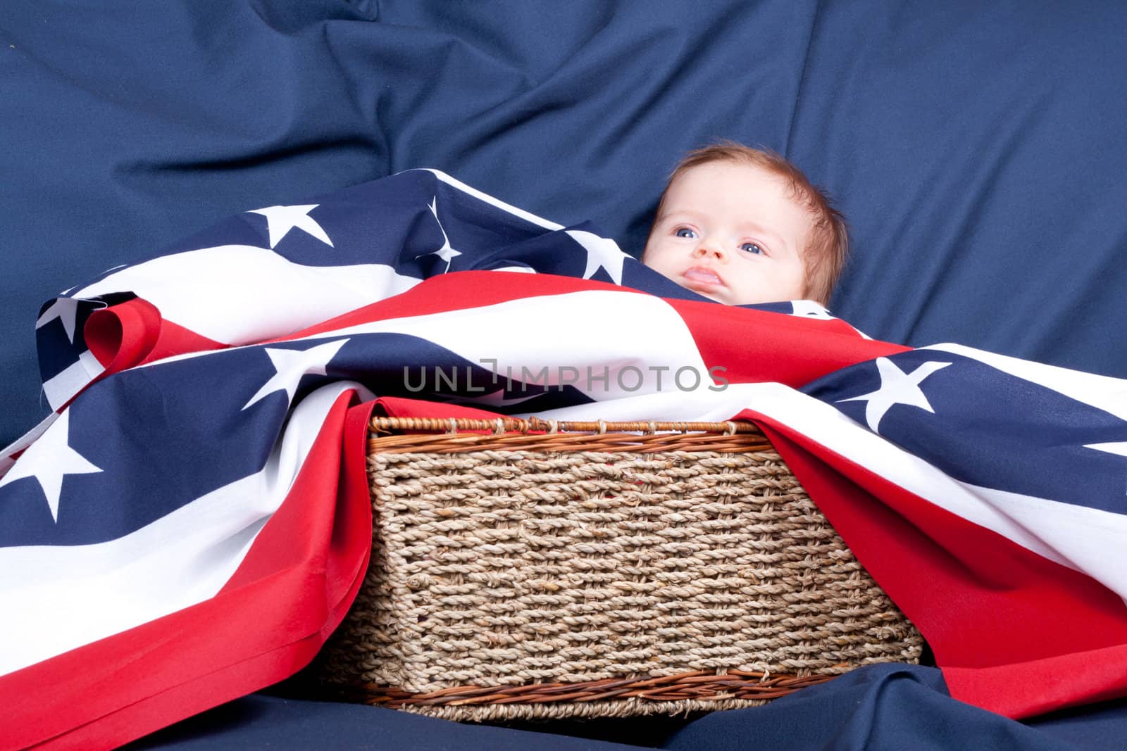 American baby laying in a basket with an american flag covering her.