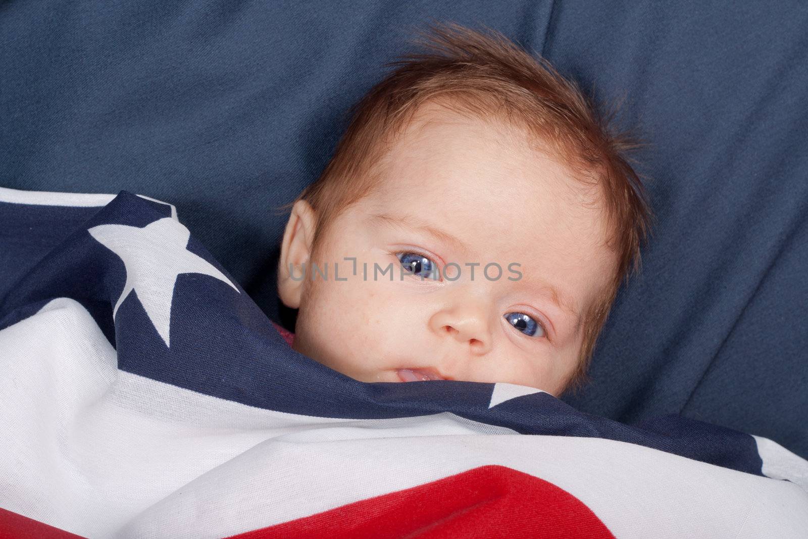 A portrait of a baby covered by an american flag.