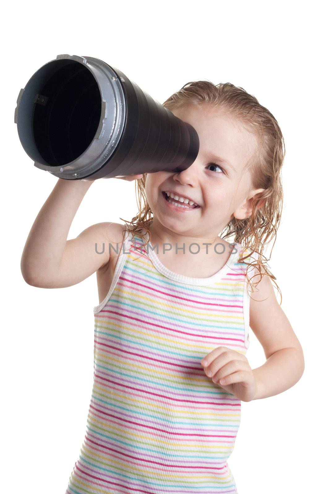 A cute girl with a smile on her face.  She is looking through a cylinder object.