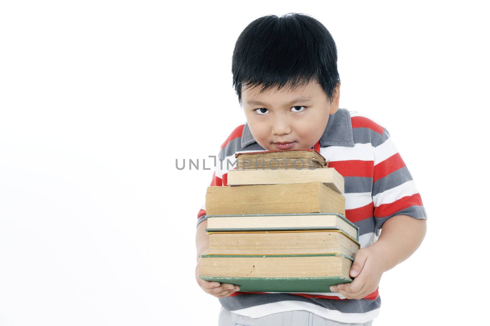 Portrait of an elementary schoolboy carrying a heavy pile of books over white background.