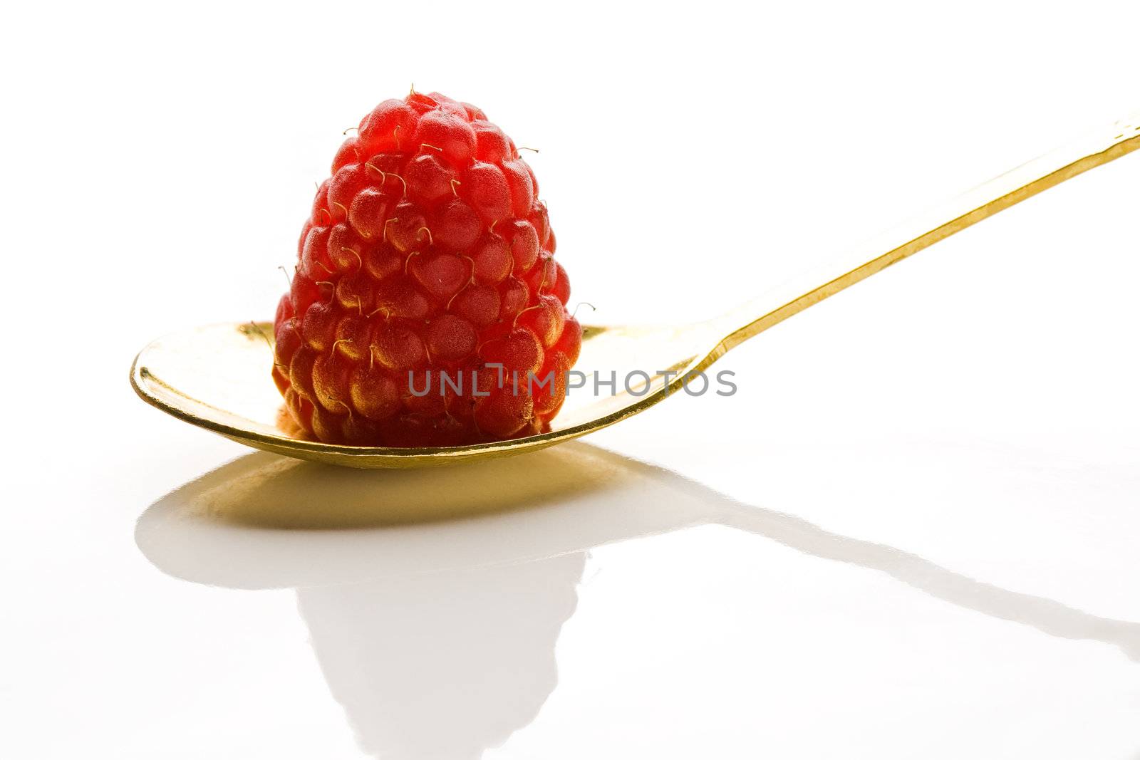 Raspberry on a gold dessert-spoon