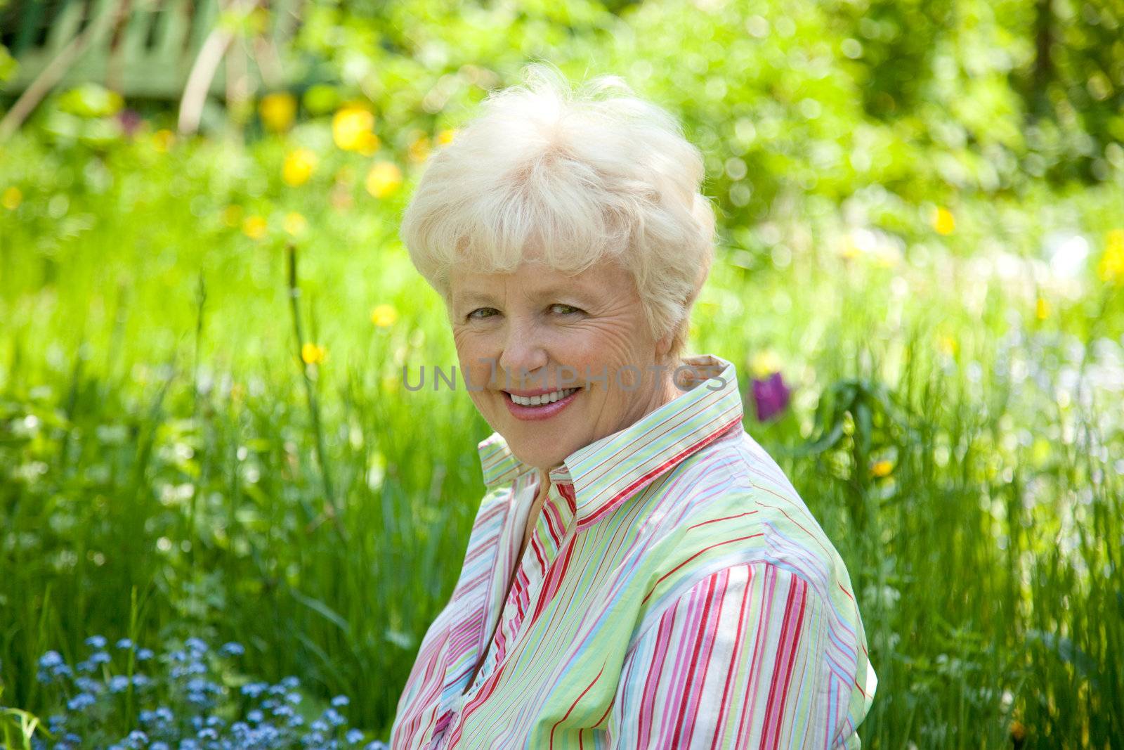 Portrait of the smiling elderly woman in  a garden
