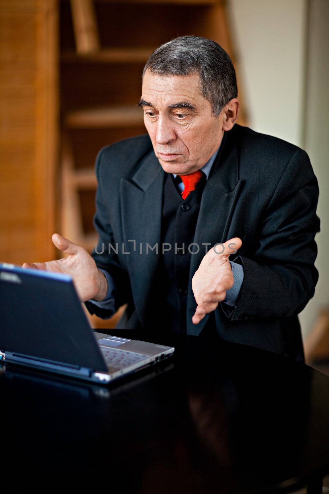 A businessman recoils from his laptop computer in horror.

