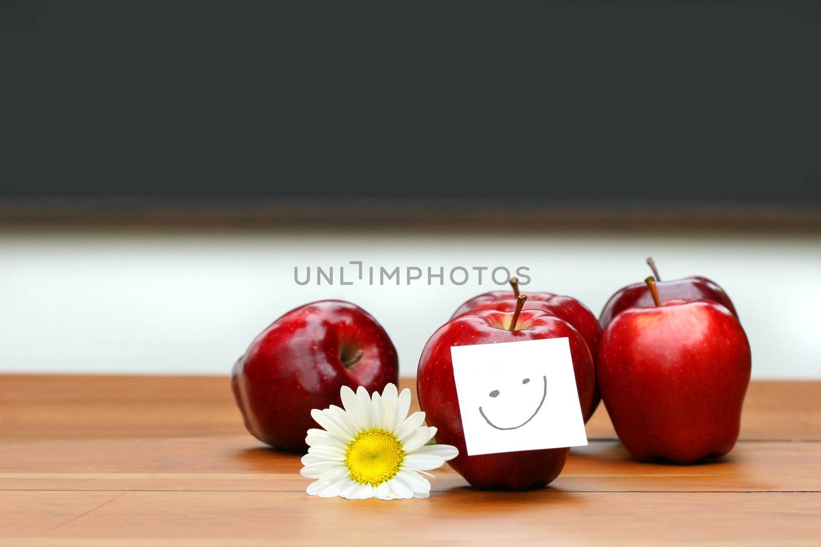 Delicious red apples on desk with blackboard in background