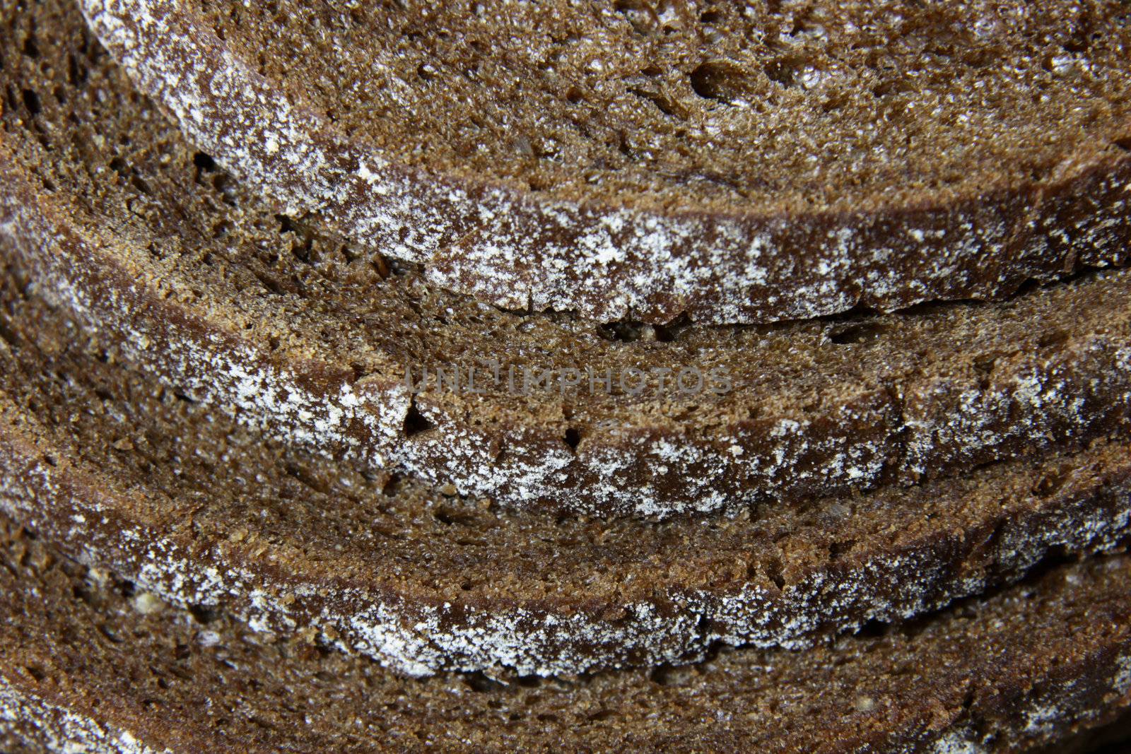A close-up of the crusts of five slices of pumpernickel bread.
