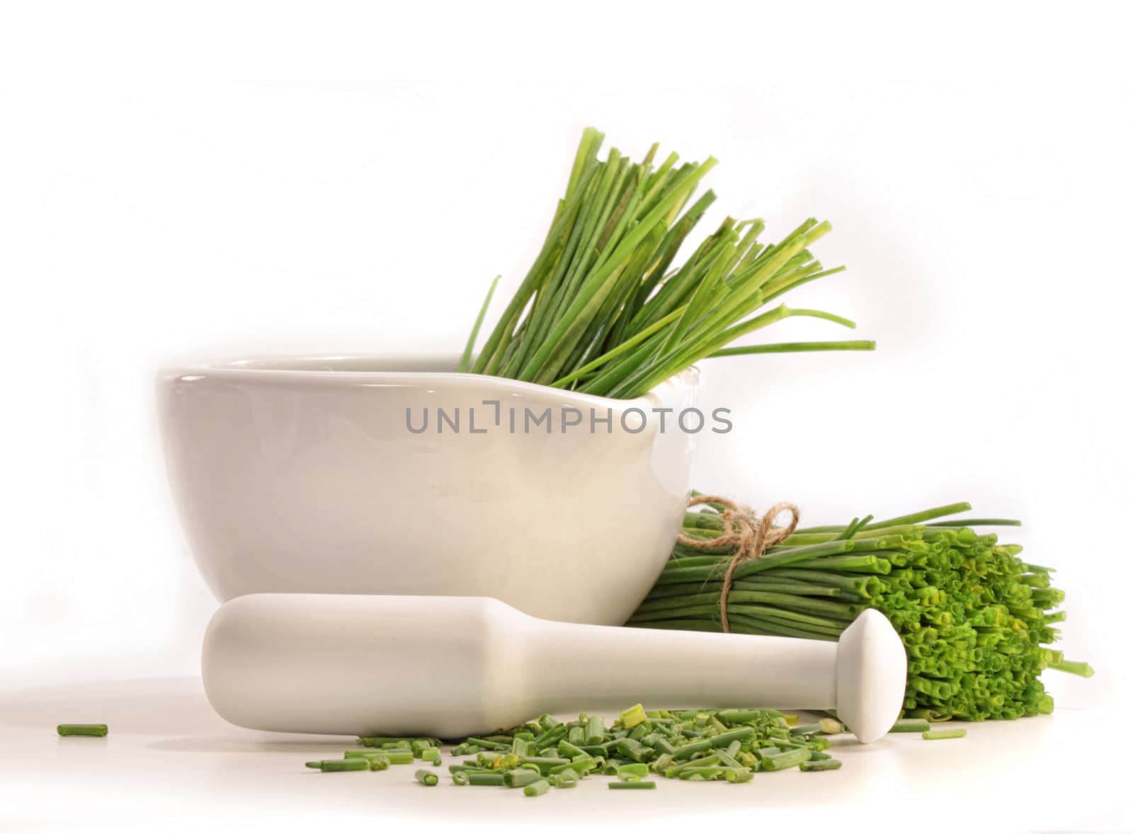 Fresh cut chives with a mortar and pestle on white