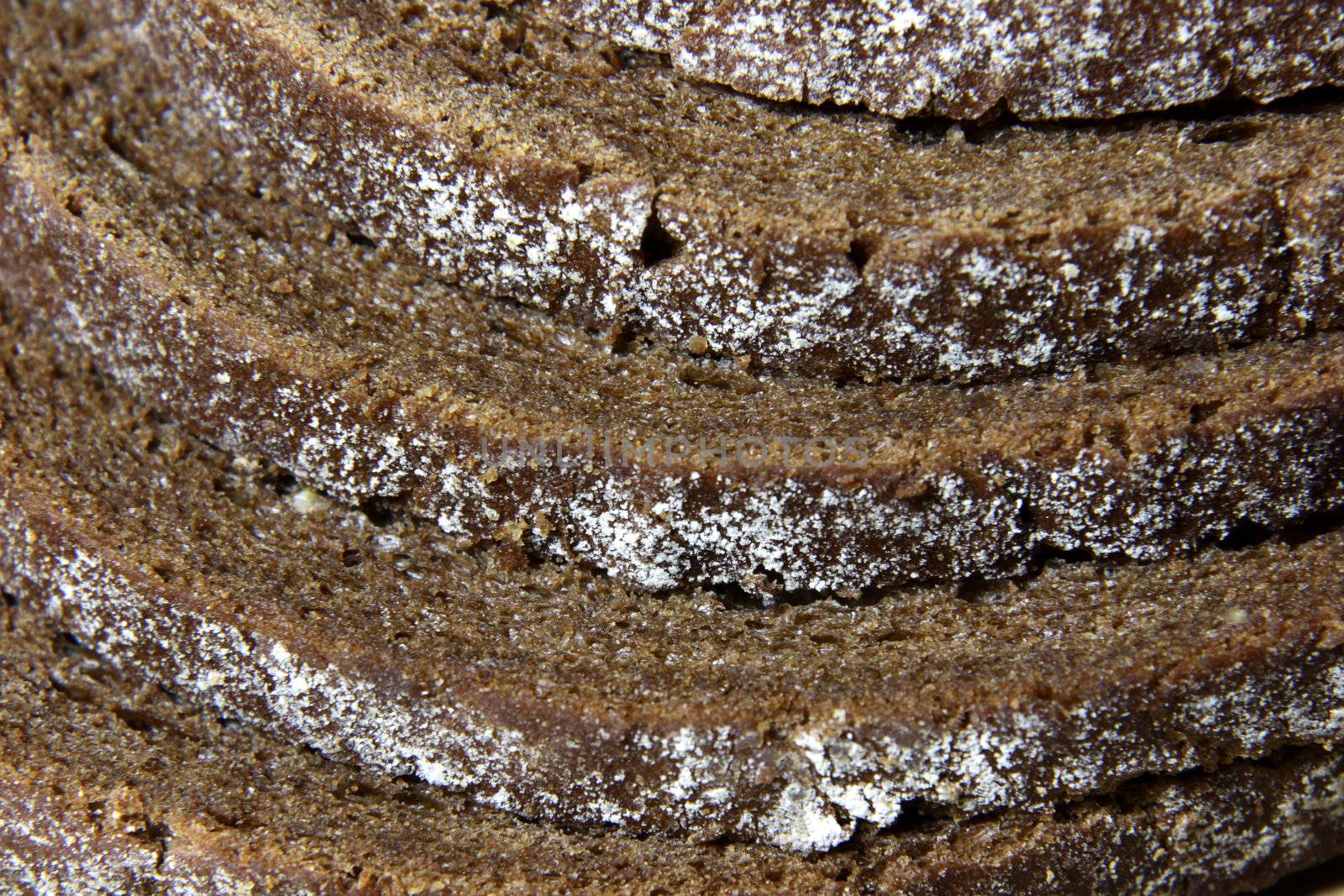 A close-up of the crusts of five slices of pumpernickel bread.
