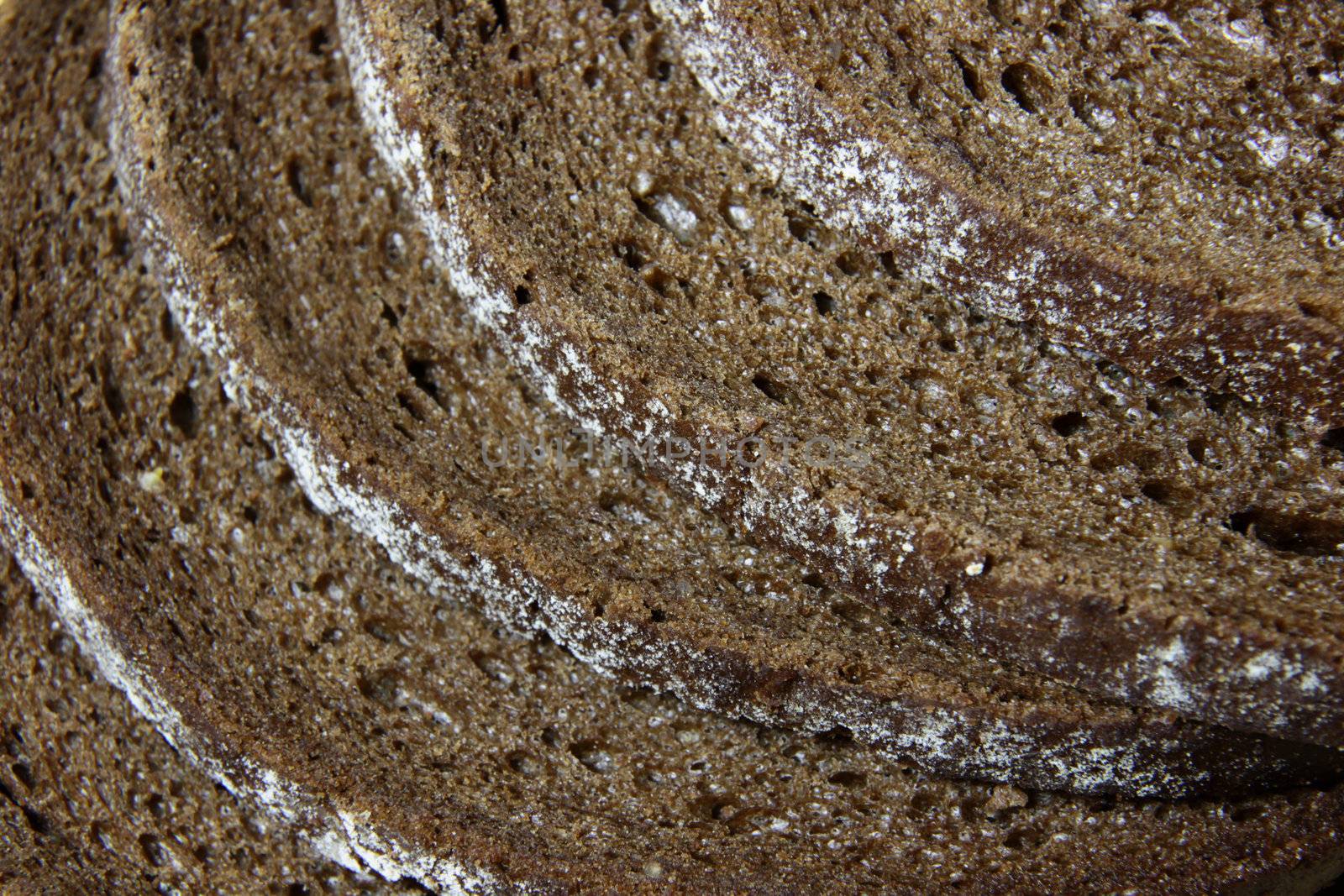 A close-up of the crusts of five slices of pumpernickel bread.
