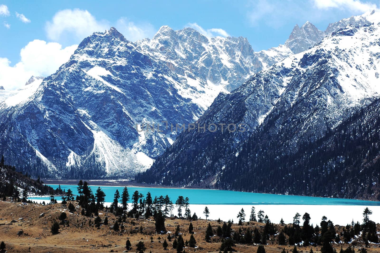 Landscape of blue lake and mountains covered with snow in winter