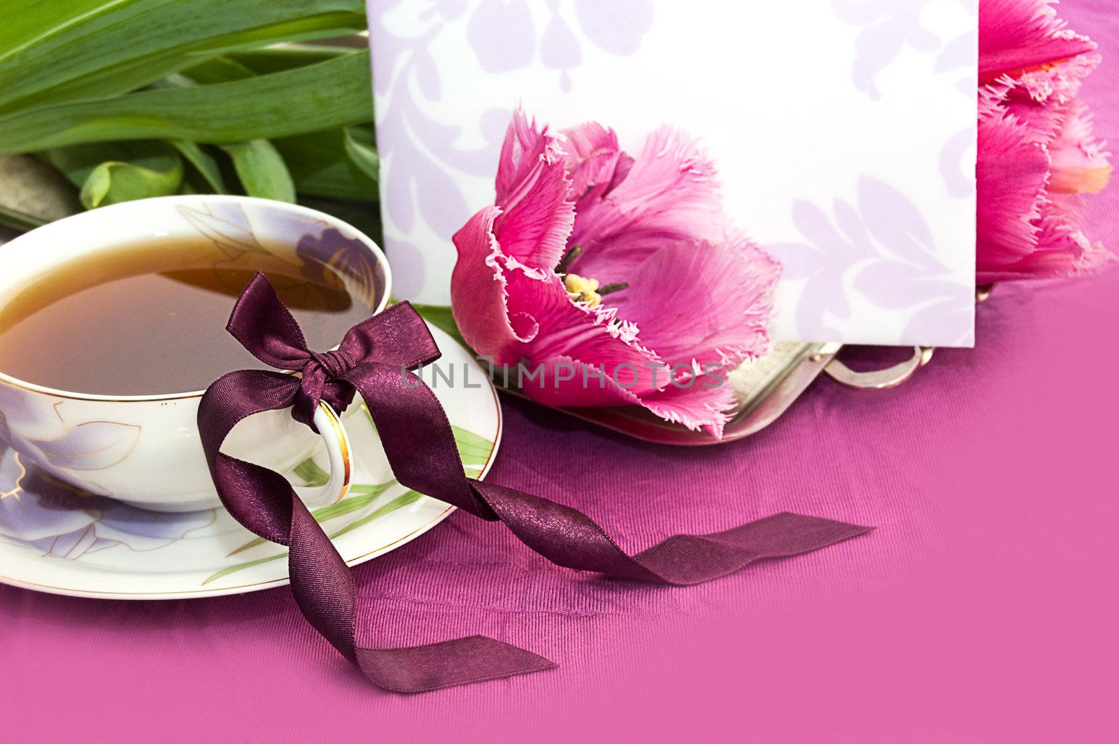 Cup of tea and magenta tulips with blank note