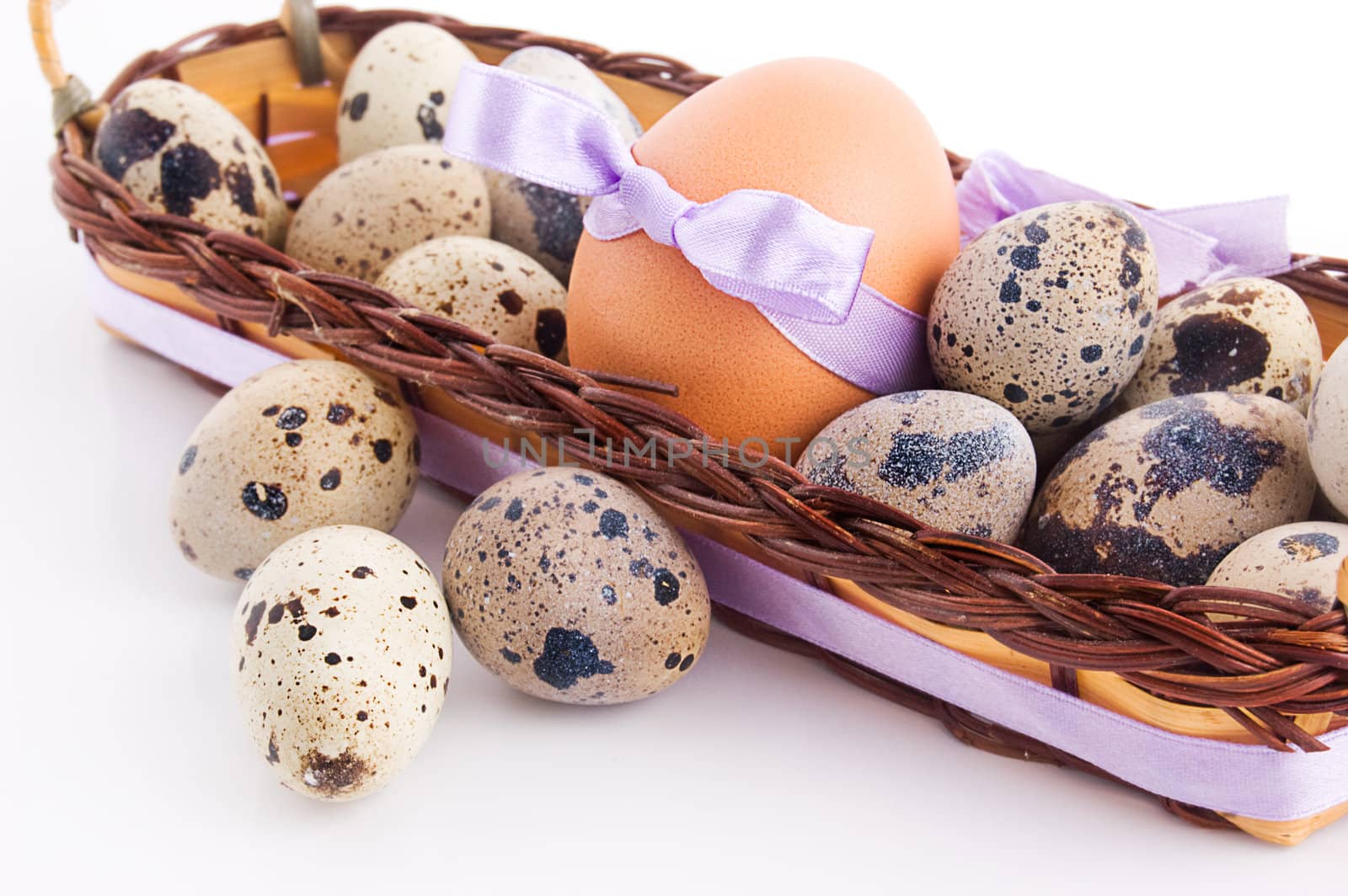 Quail and chicken eggs in basket over white