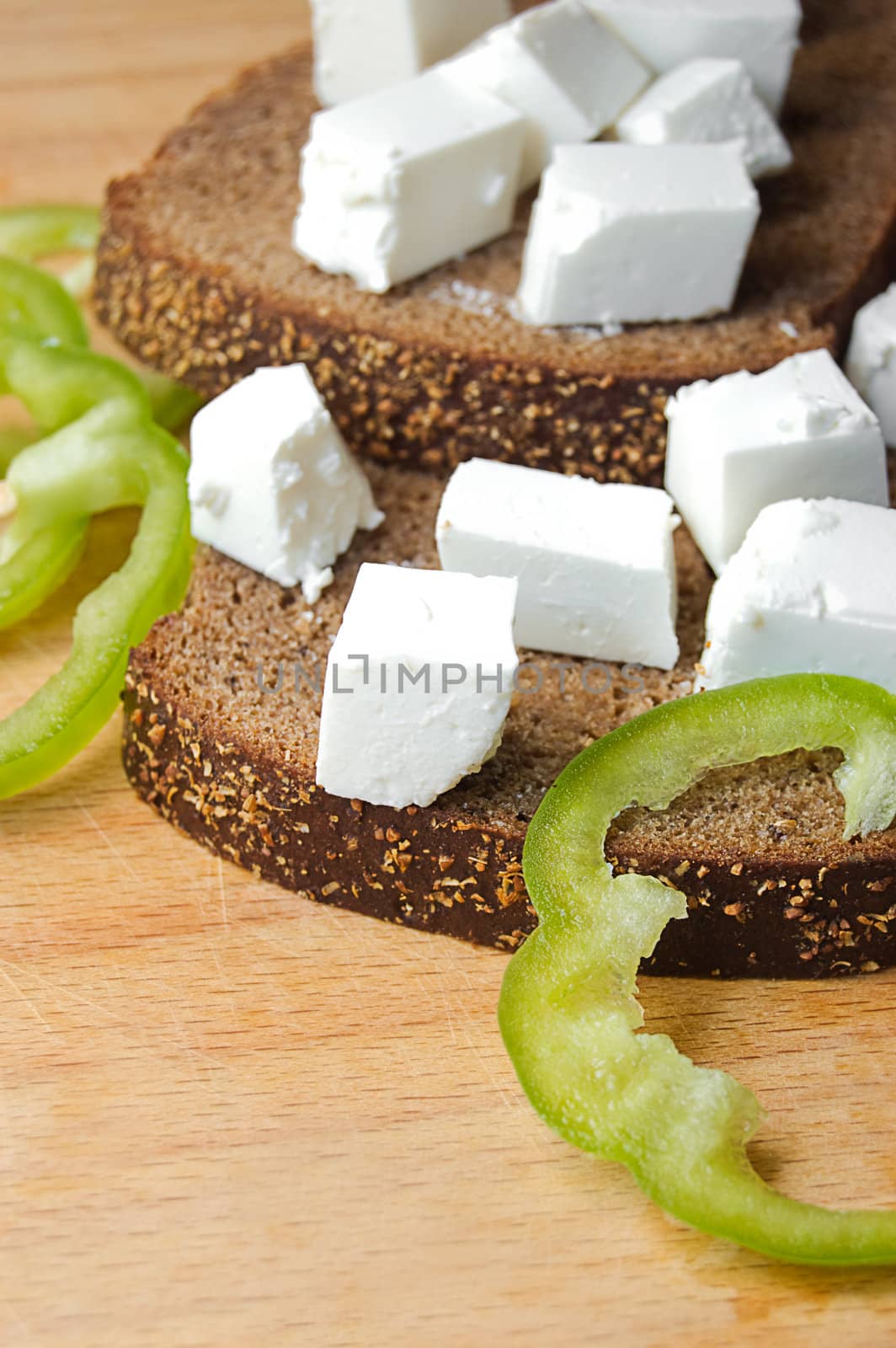 Feta cheese cubes with pepper and bread on wooden board