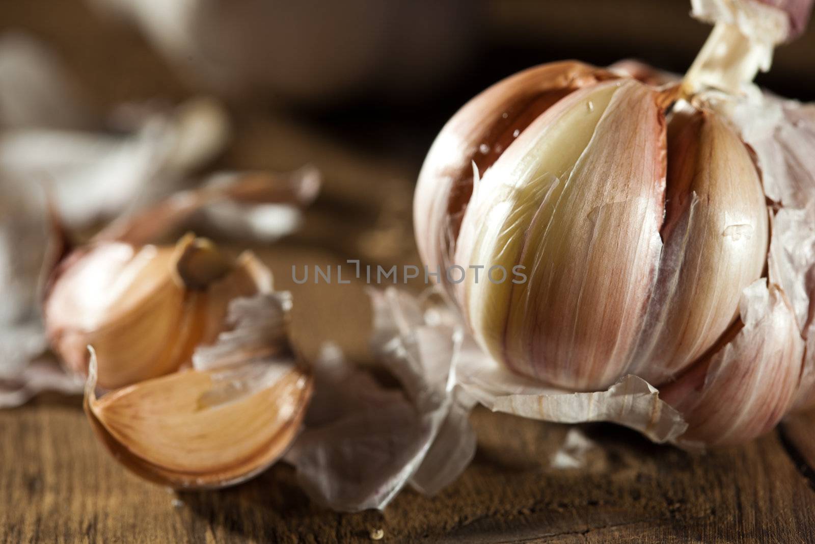 A ball of garlic with some cloves lying next to it on wood